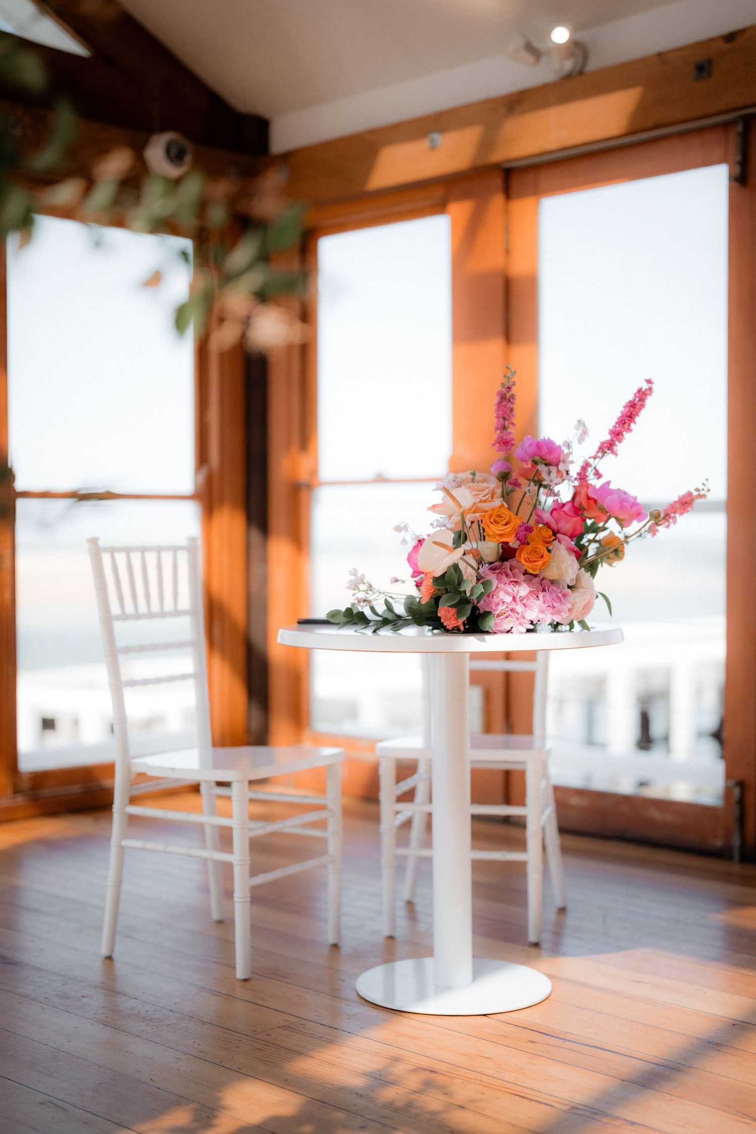 Rustic wedding venue interior with white chairs and floral centerpieces.