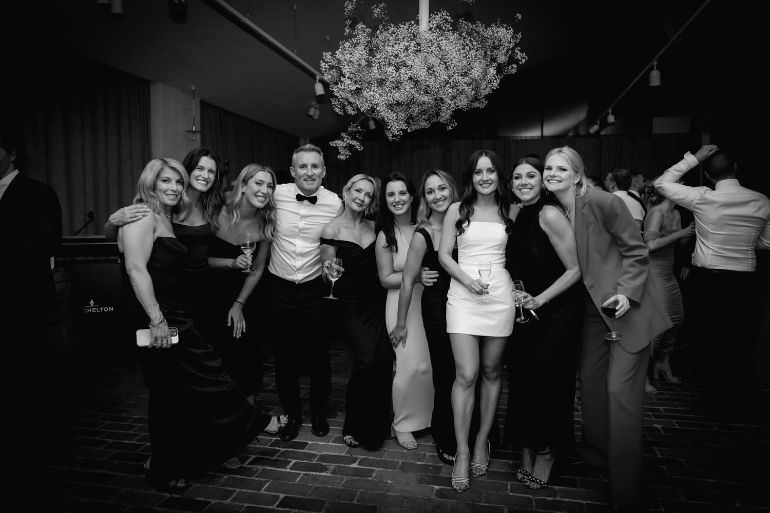 Wedding party poses together at reception in black and white photography.