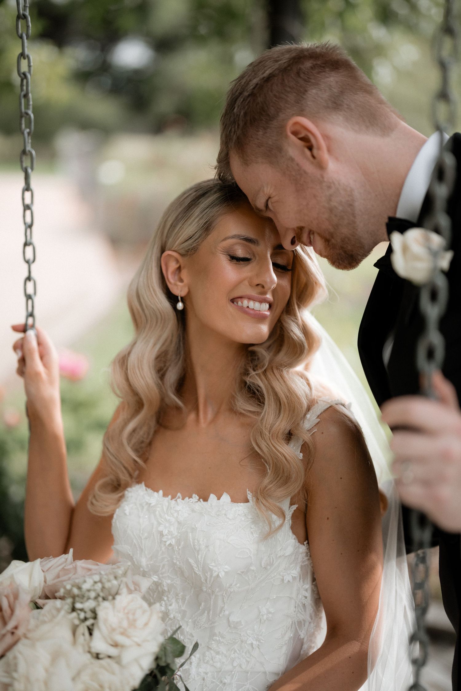 A romantic moment shared on a garden swing during a wedding photoshoot.
