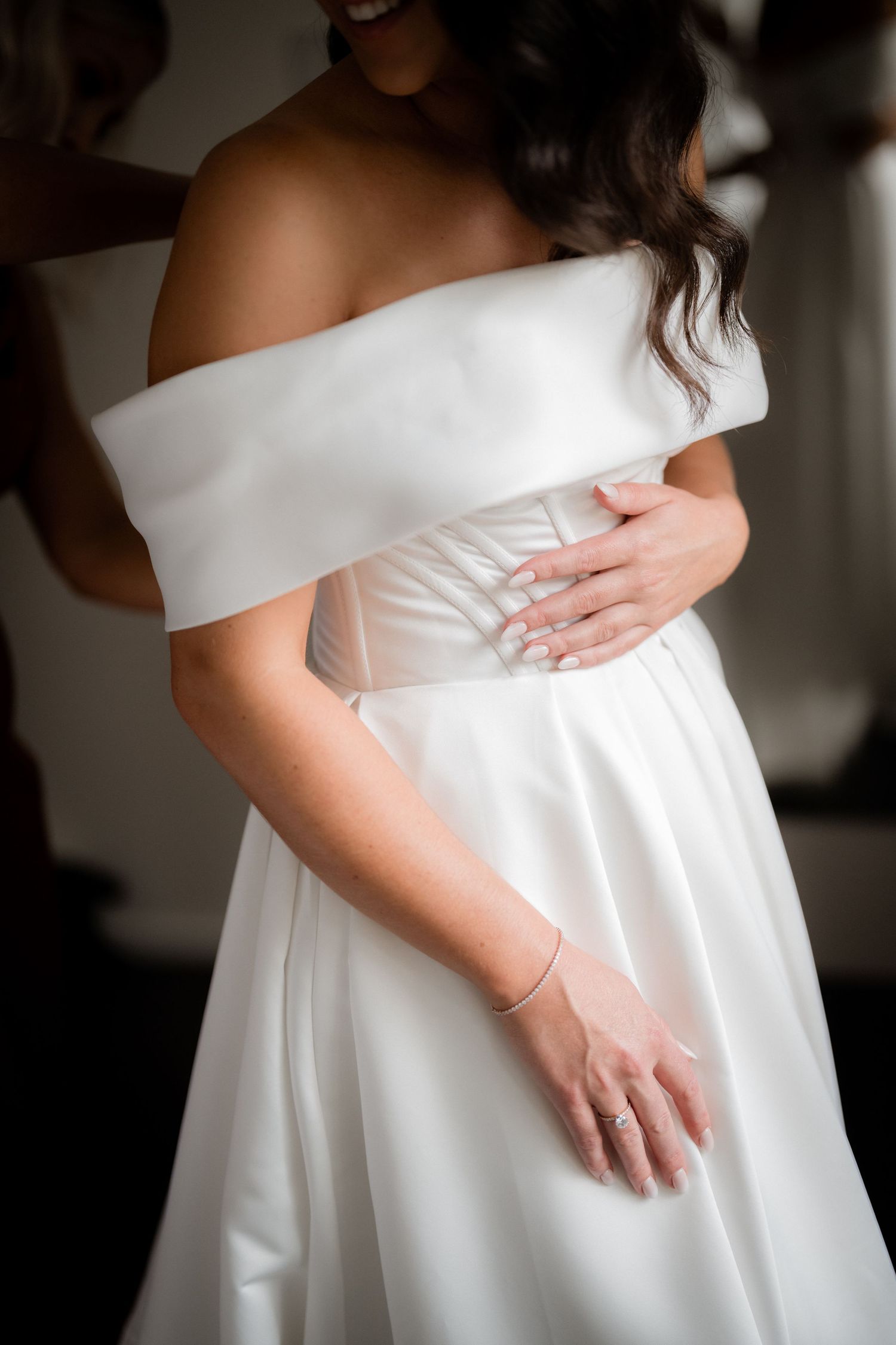 Elegant off-shoulder white wedding dress with folded neckline detail shown in close-up.