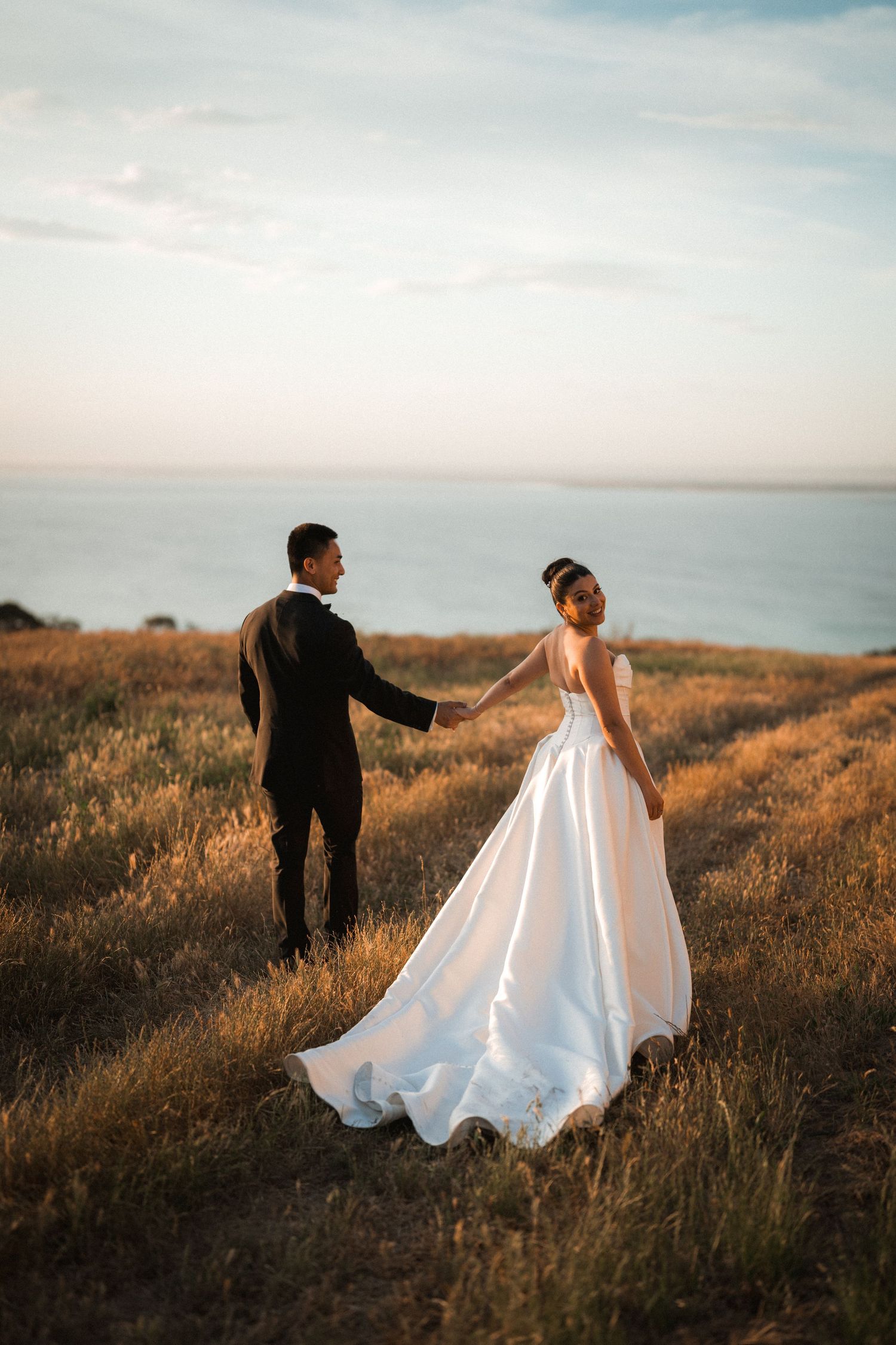 Sunset wedding photos in a golden field overlooking the ocean.