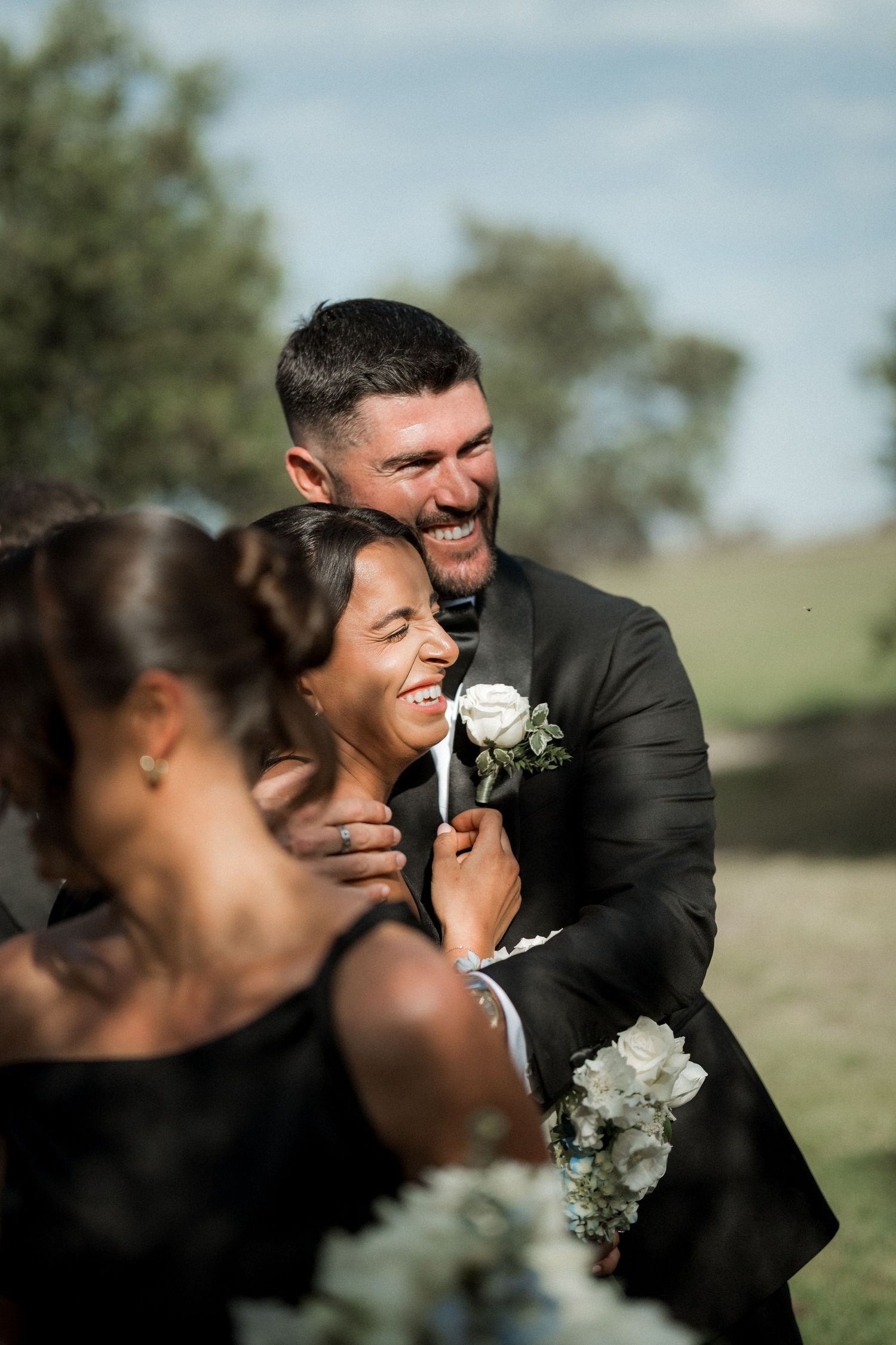 A joyful wedding couple shares intimate laughs and tender moments during their outdoor photo session.