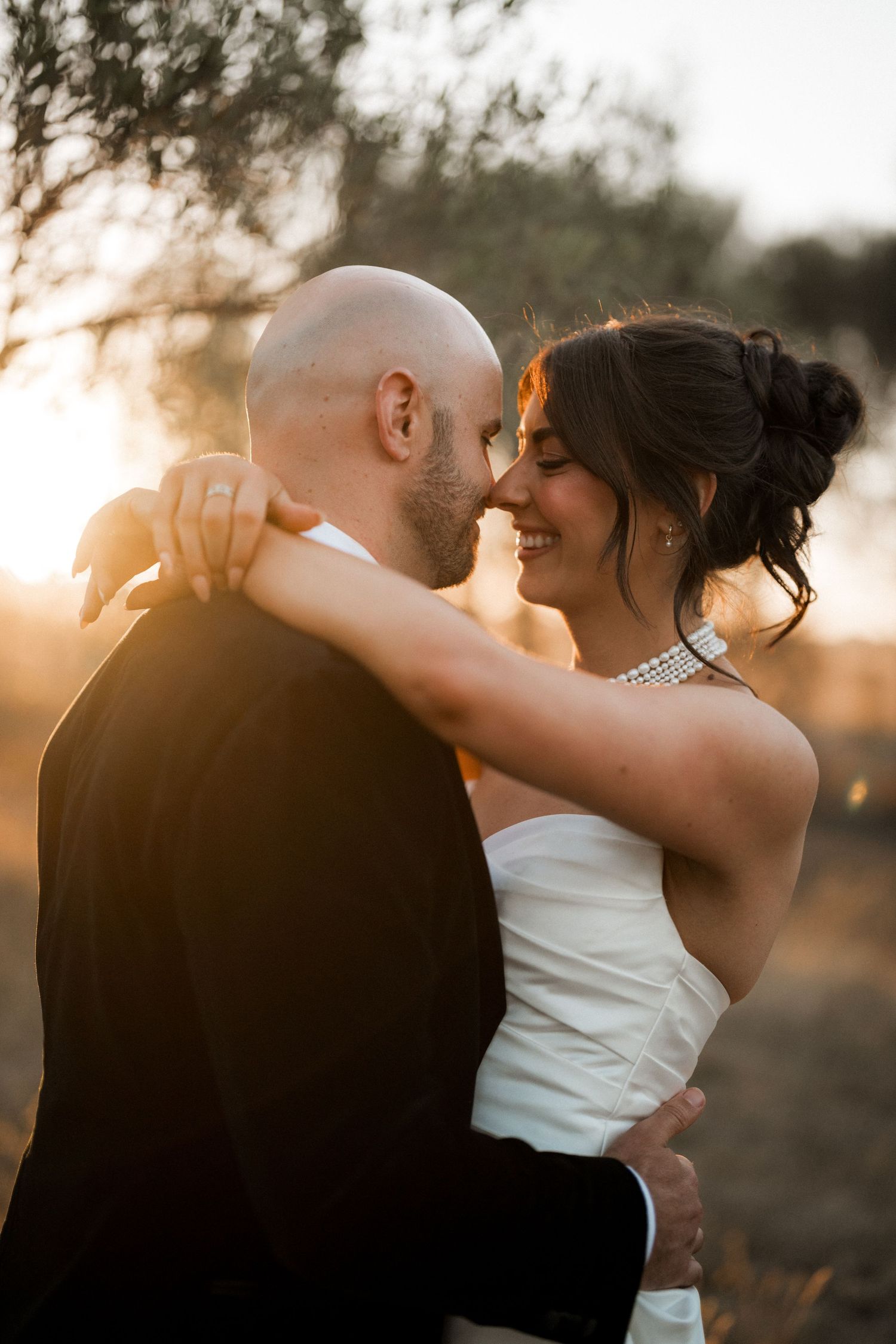 Romantic sunset embrace captured during wedding photoshoot in natural setting.