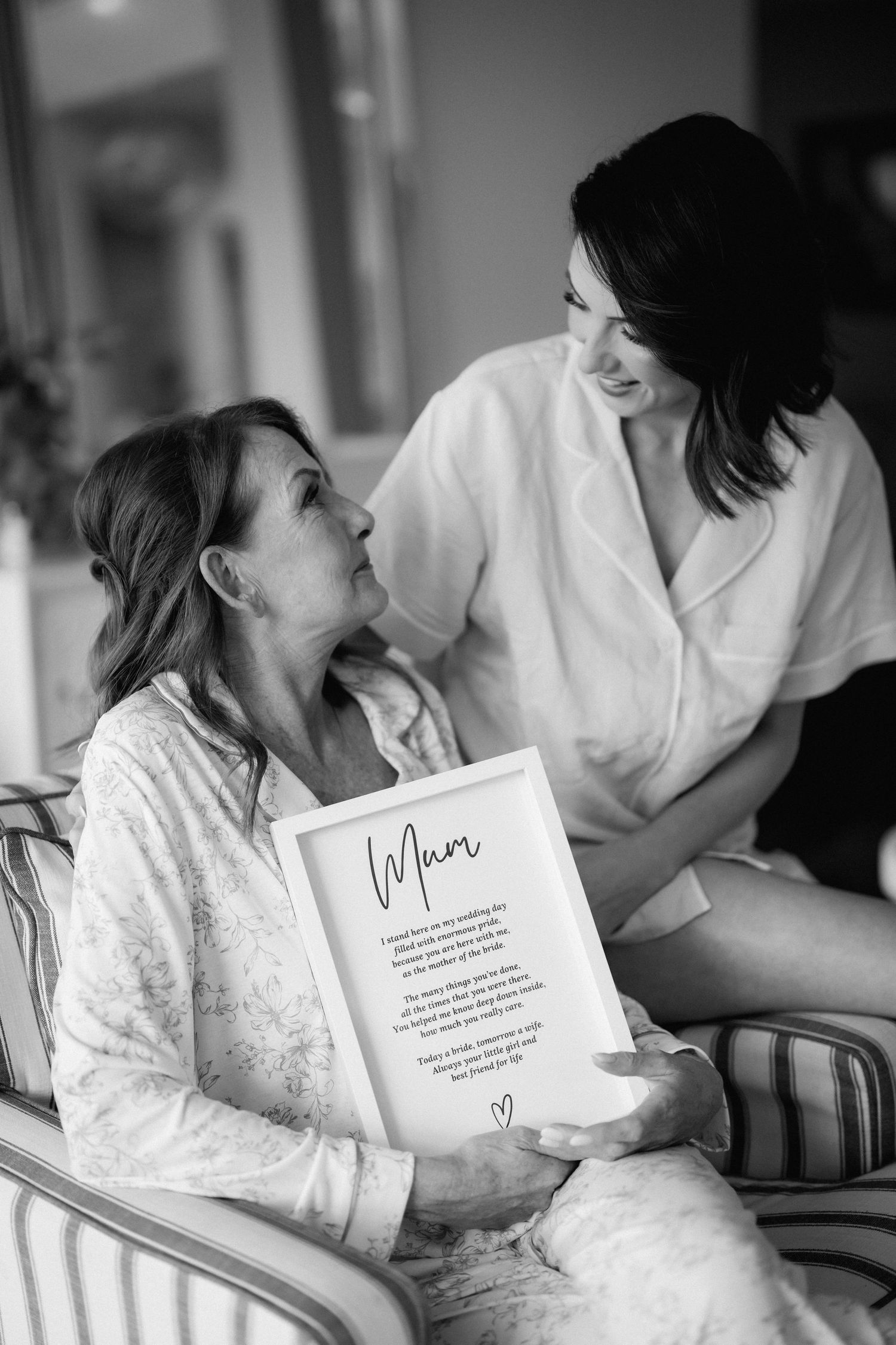 Black and white photo showing a touching moment between two people sharing a letter while sitting in a comfortable setting.