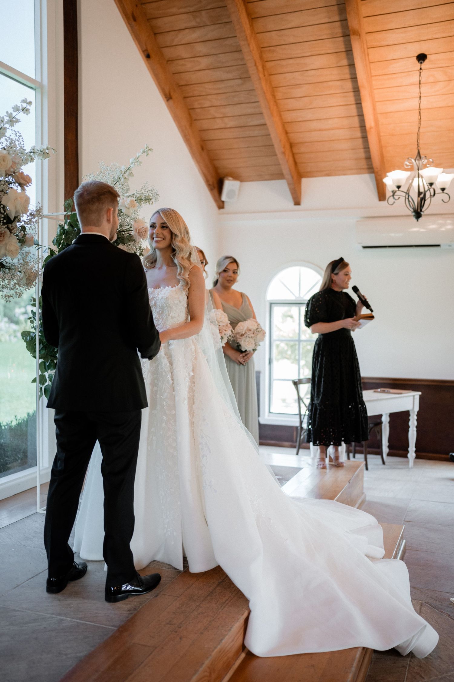 A bride and groom exchanging vows in a rustic chapel with wooden beams and natural light.