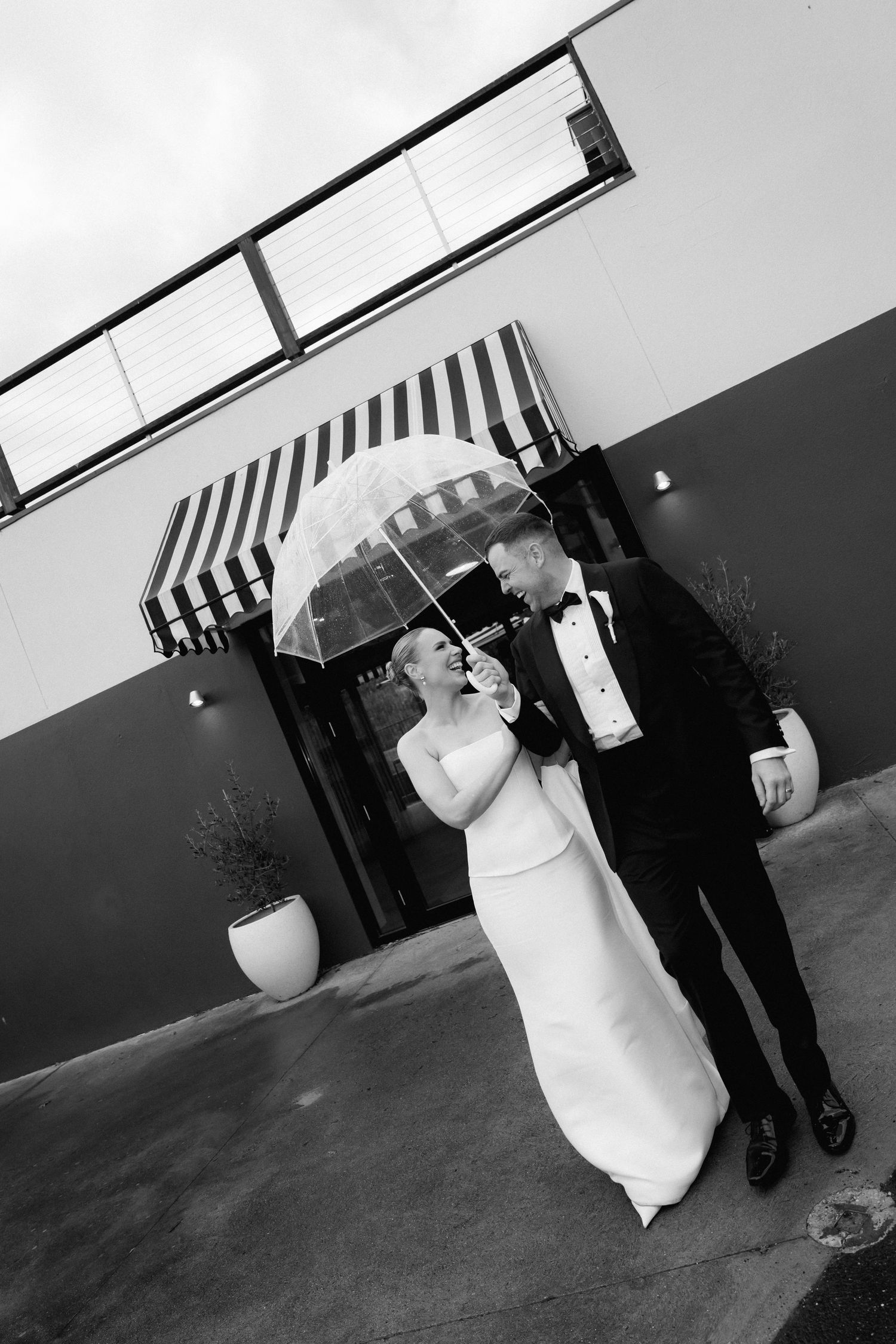 Black and white photos of a rainy wedding day with umbrellas and formal attire.