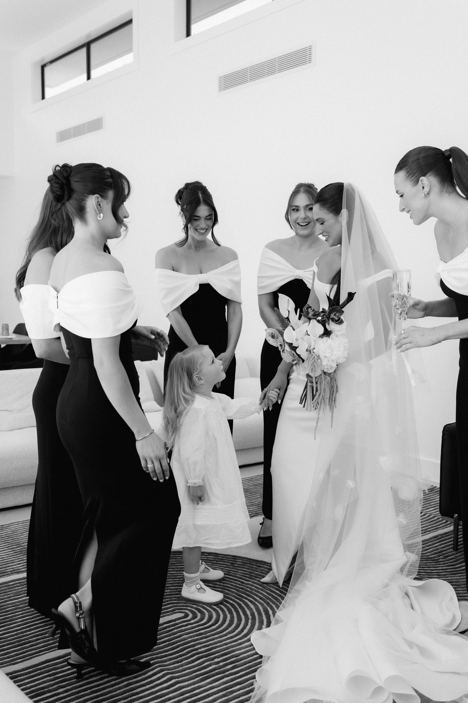 Wedding party members in black and white attire gather in a circle during a dance lesson.