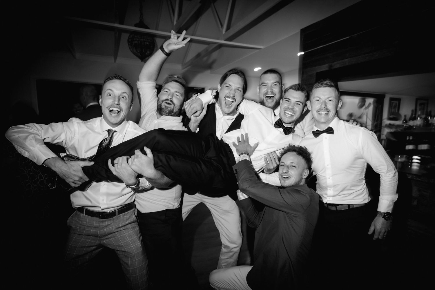 Black and white photo collage showing a group of people in a celebratory mood at what appears to be a party or gathering.