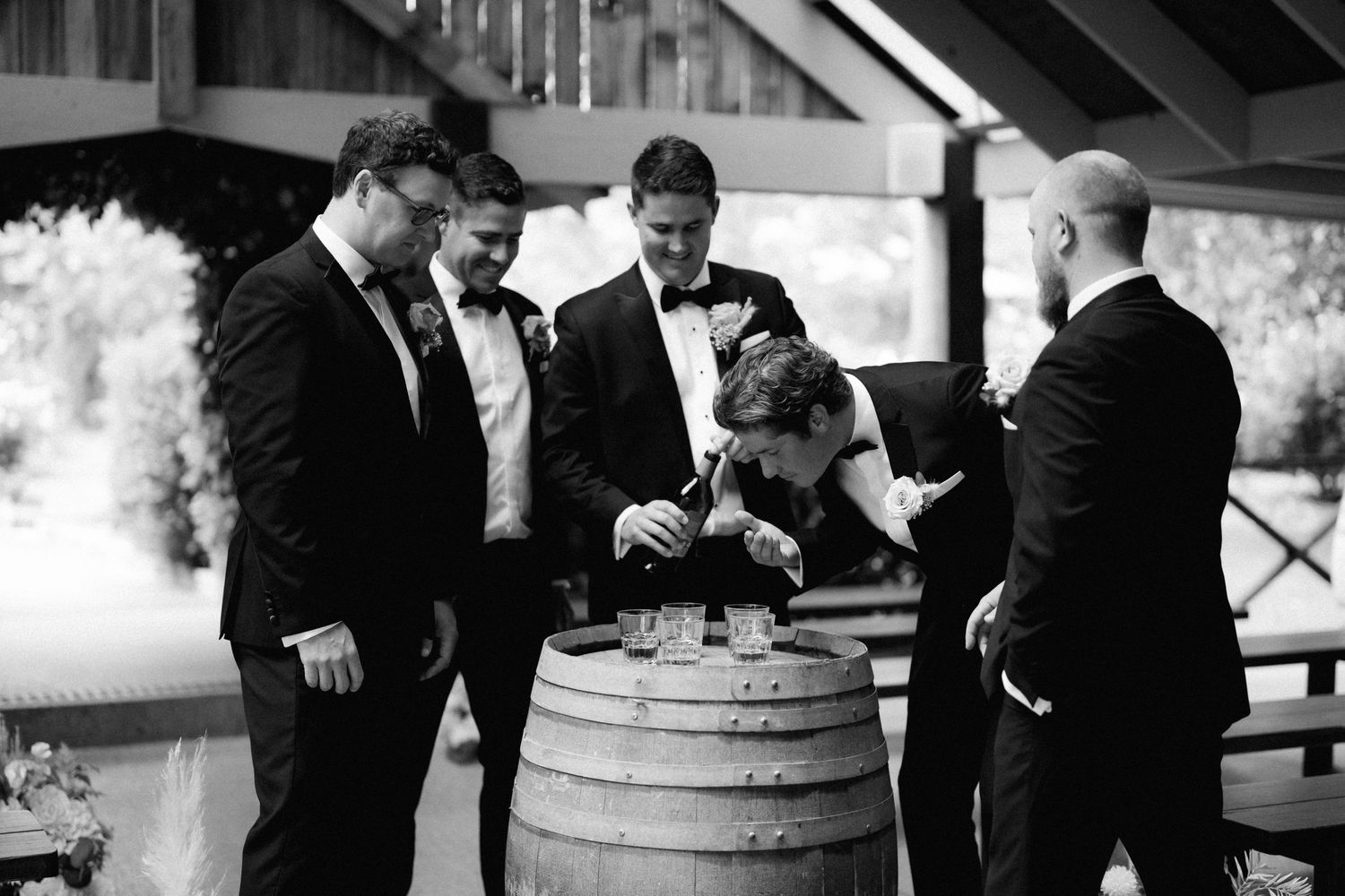 Black and white wedding photo collage showing groomsmen preparing and adjusting formal attire before ceremony.