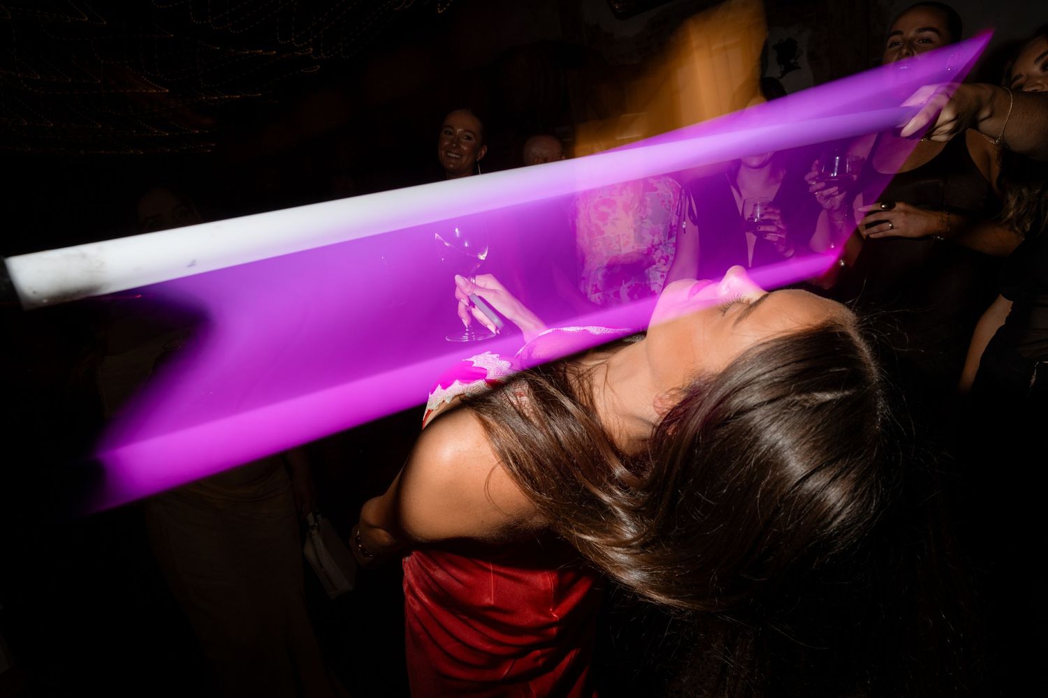 Purple glow sticks lighting up a dark dance floor at wedding reception.