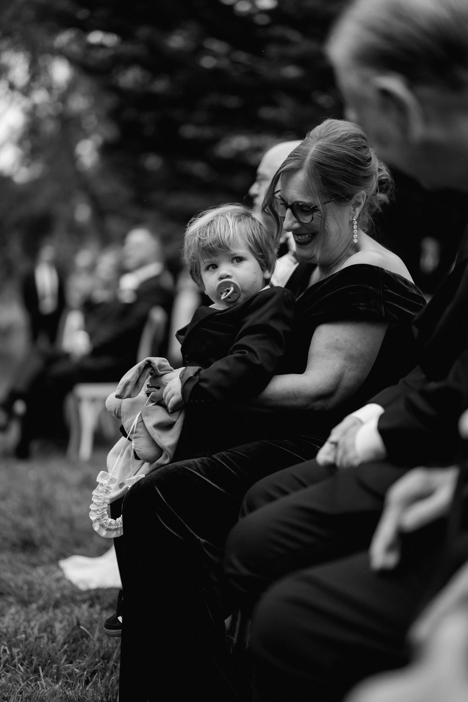Wedding party members share emotional embraces during outdoor celebration.