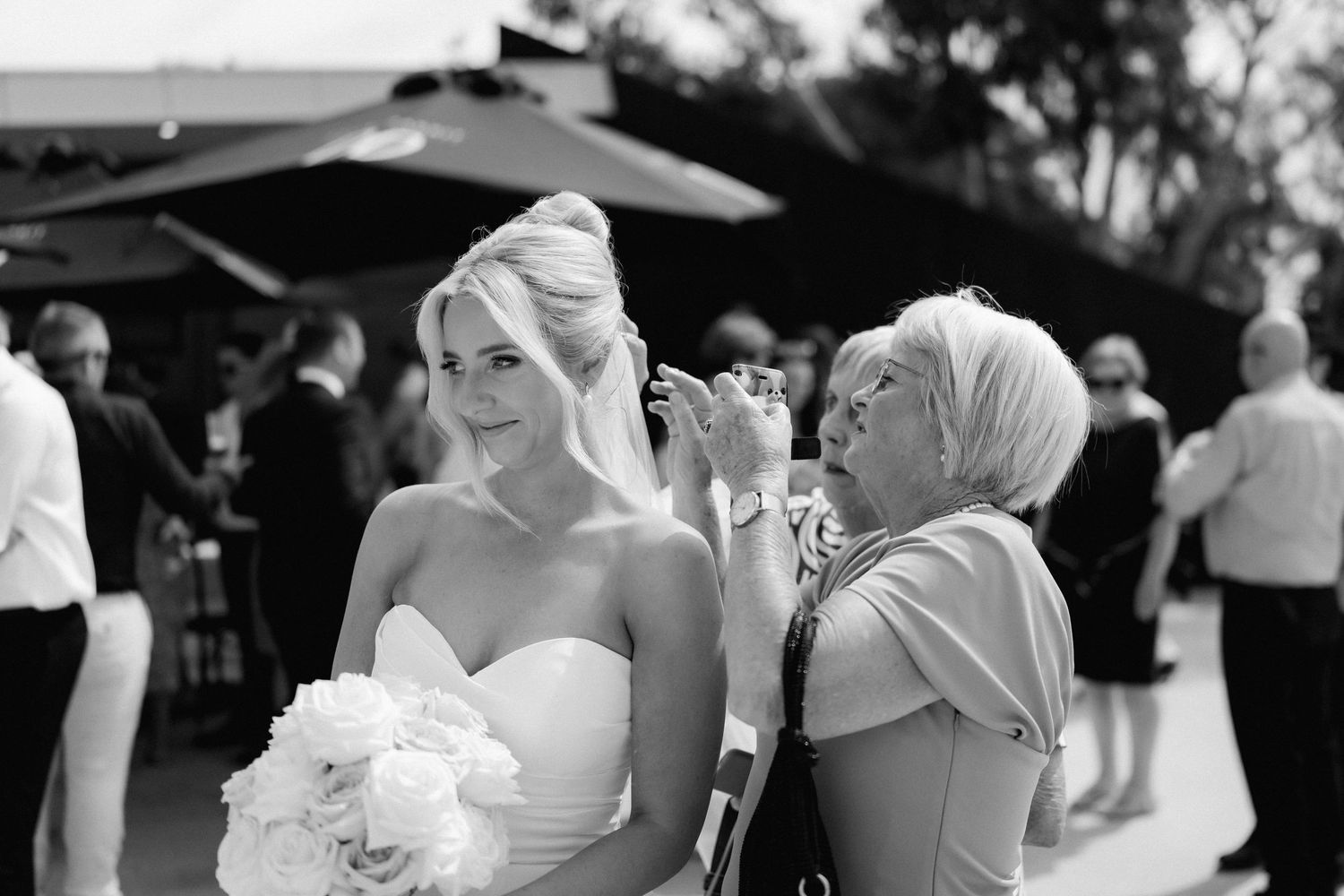 A candid black and white moment shared between a bride and wedding guest during celebrations.
