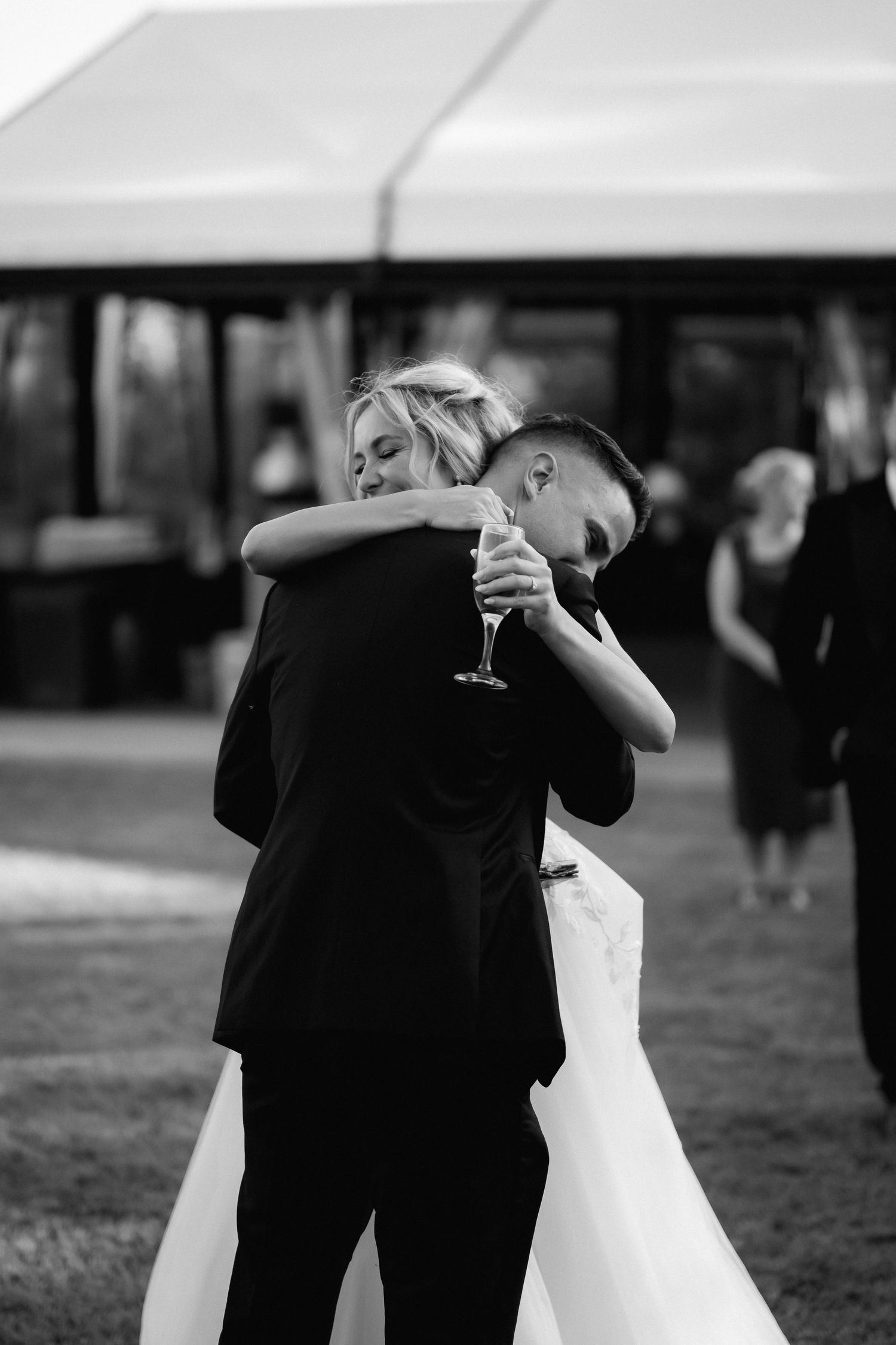 A bride and groom share an intimate dance while holding champagne glasses at their wedding reception.
