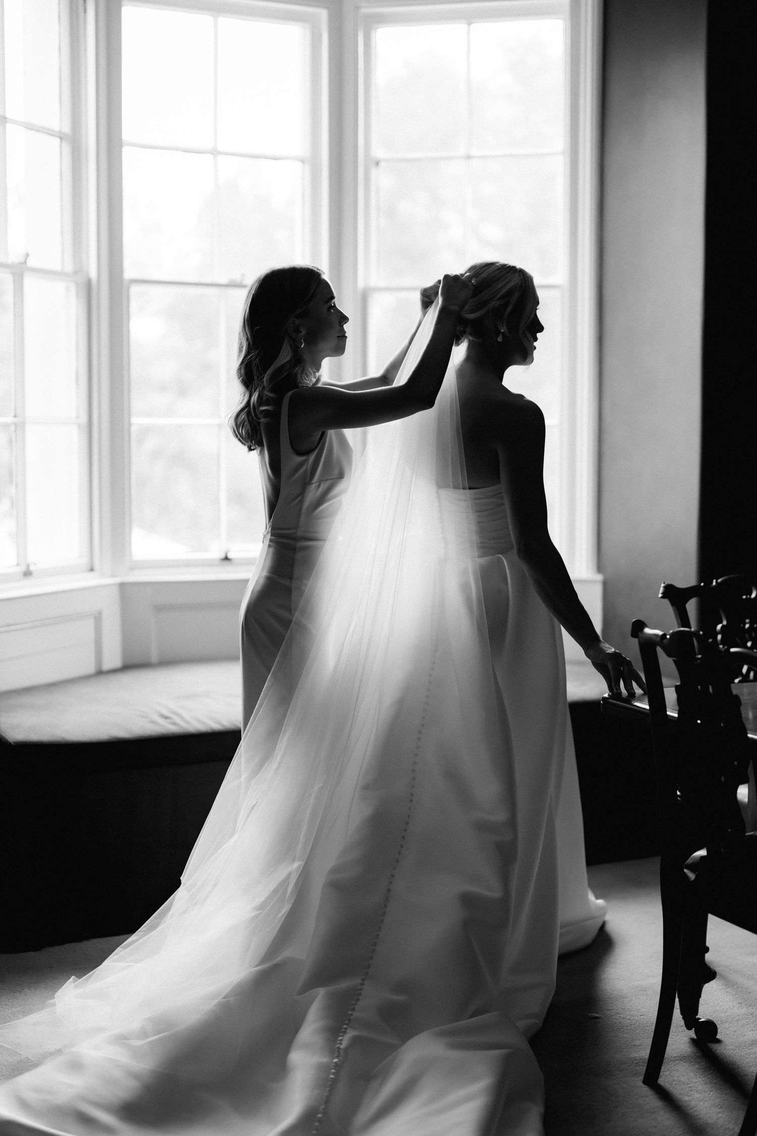 Silhouette of wedding preparation scene by large windows in black and white.