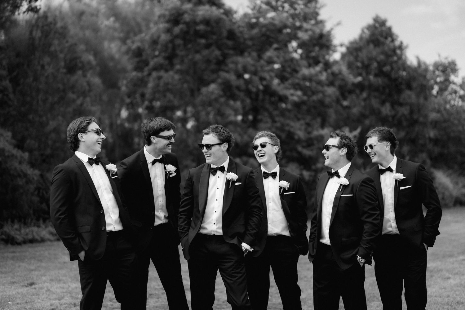 A black and white photo sequence showing a group in formal tuxedos walking and posing together outdoors.
