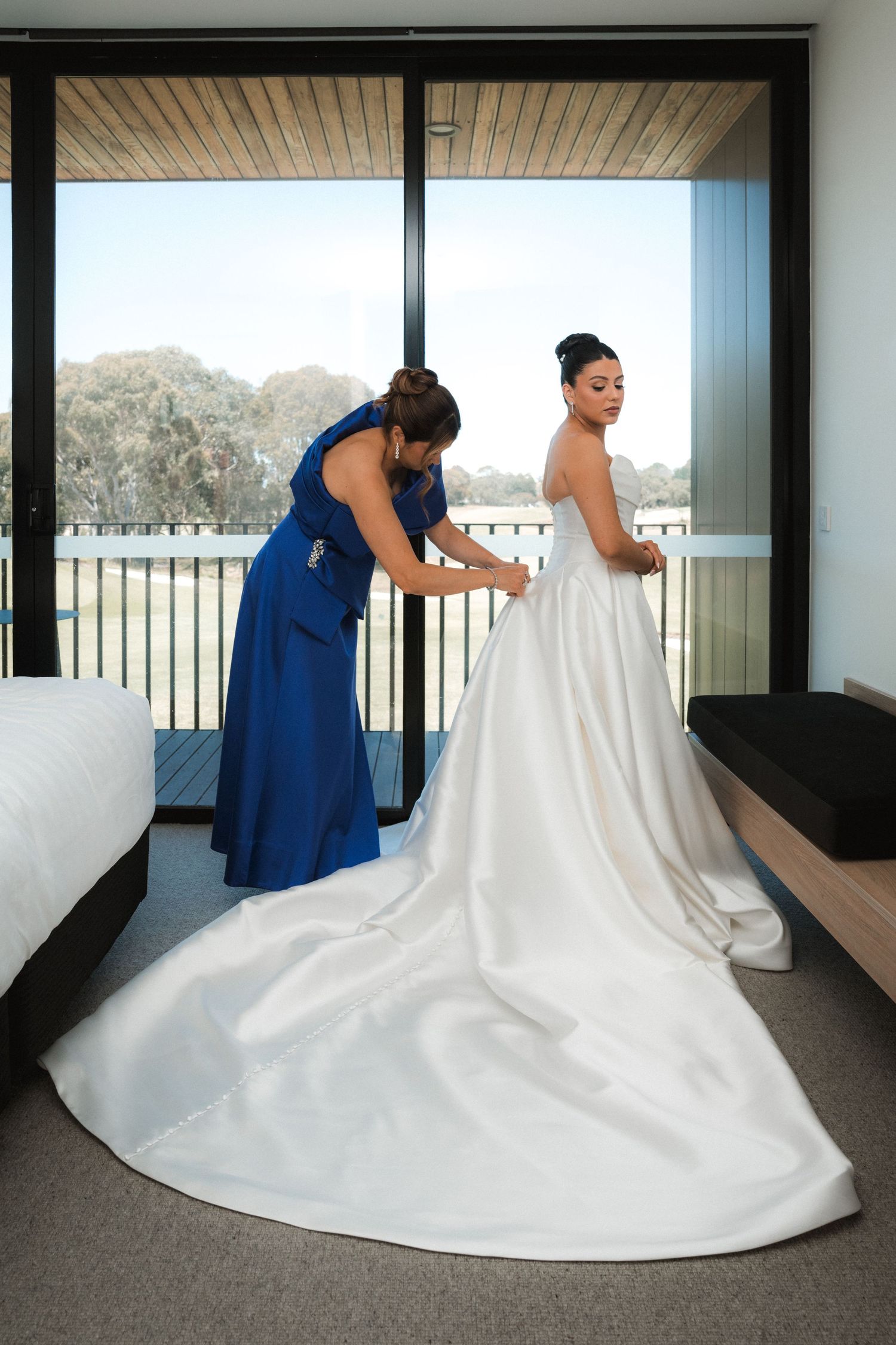 A sequence showing a wedding dress being arranged and fluffed on grey carpet with blue accents.