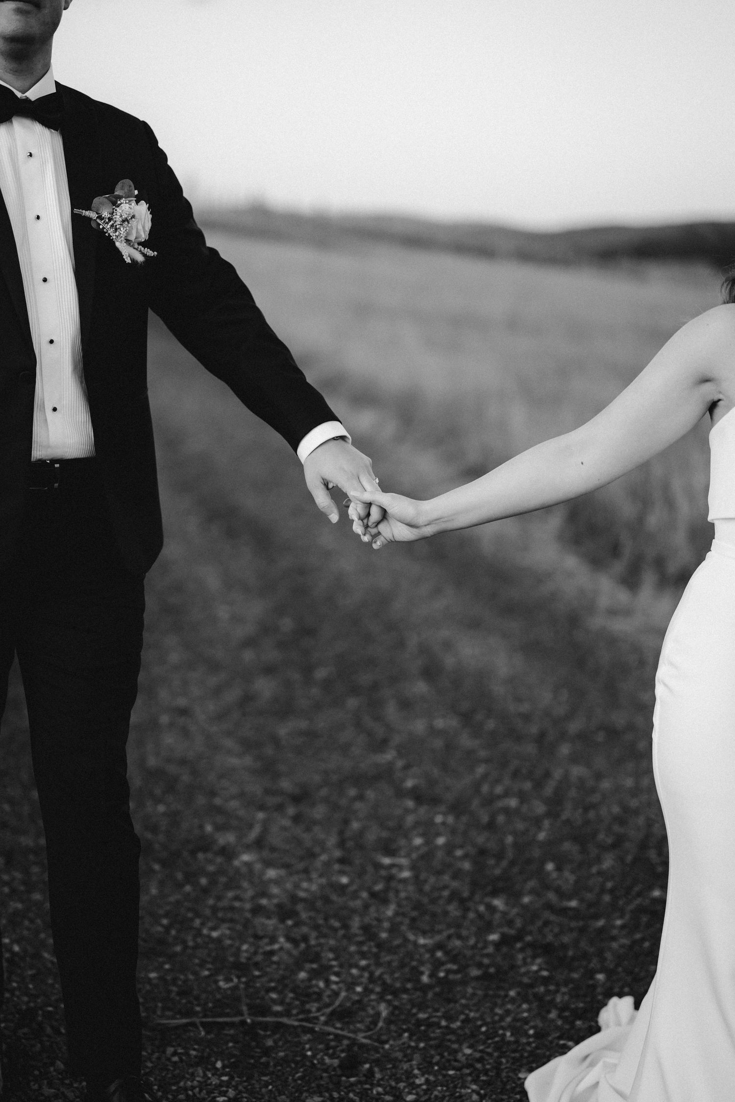 Artistic black and white wedding photos capture romantic moments between couple on textured ground.