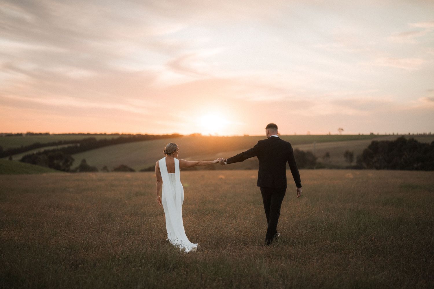 A silhouetted figure walks through a golden field at sunset with a dreamy, ethereal atmosphere.