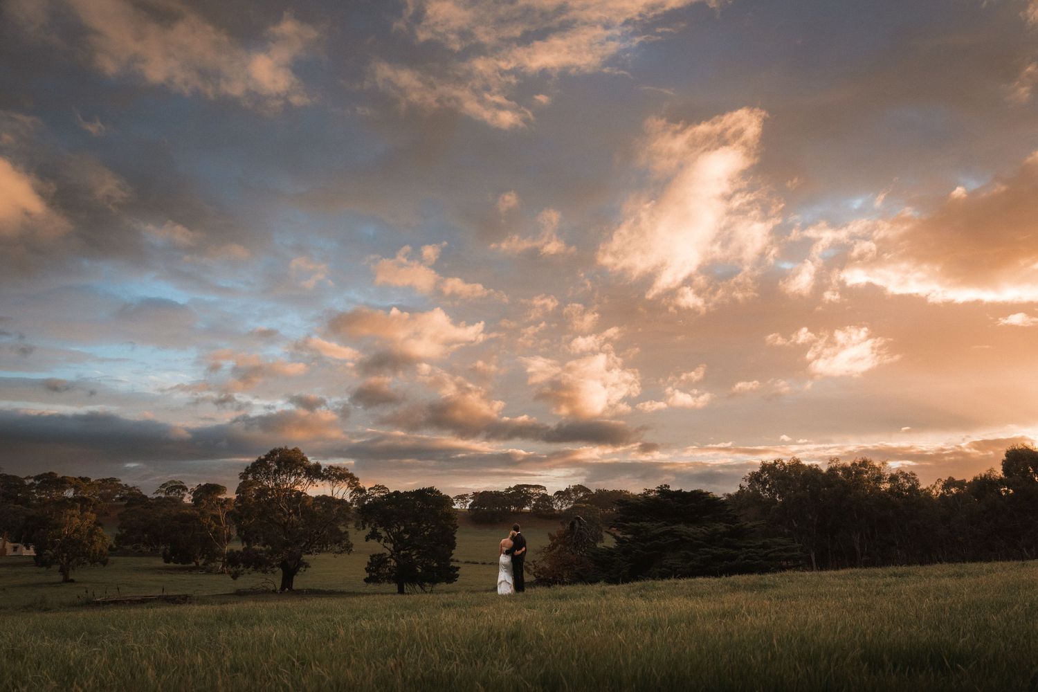 Panoramic sunset landscape with dramatic clouds over rolling hills.
