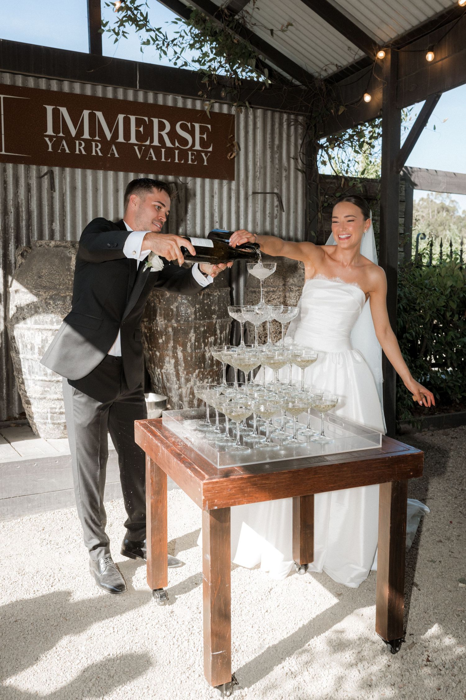 Newlyweds pour champagne into a tower of glasses at Immerse Yarra Valley winery.