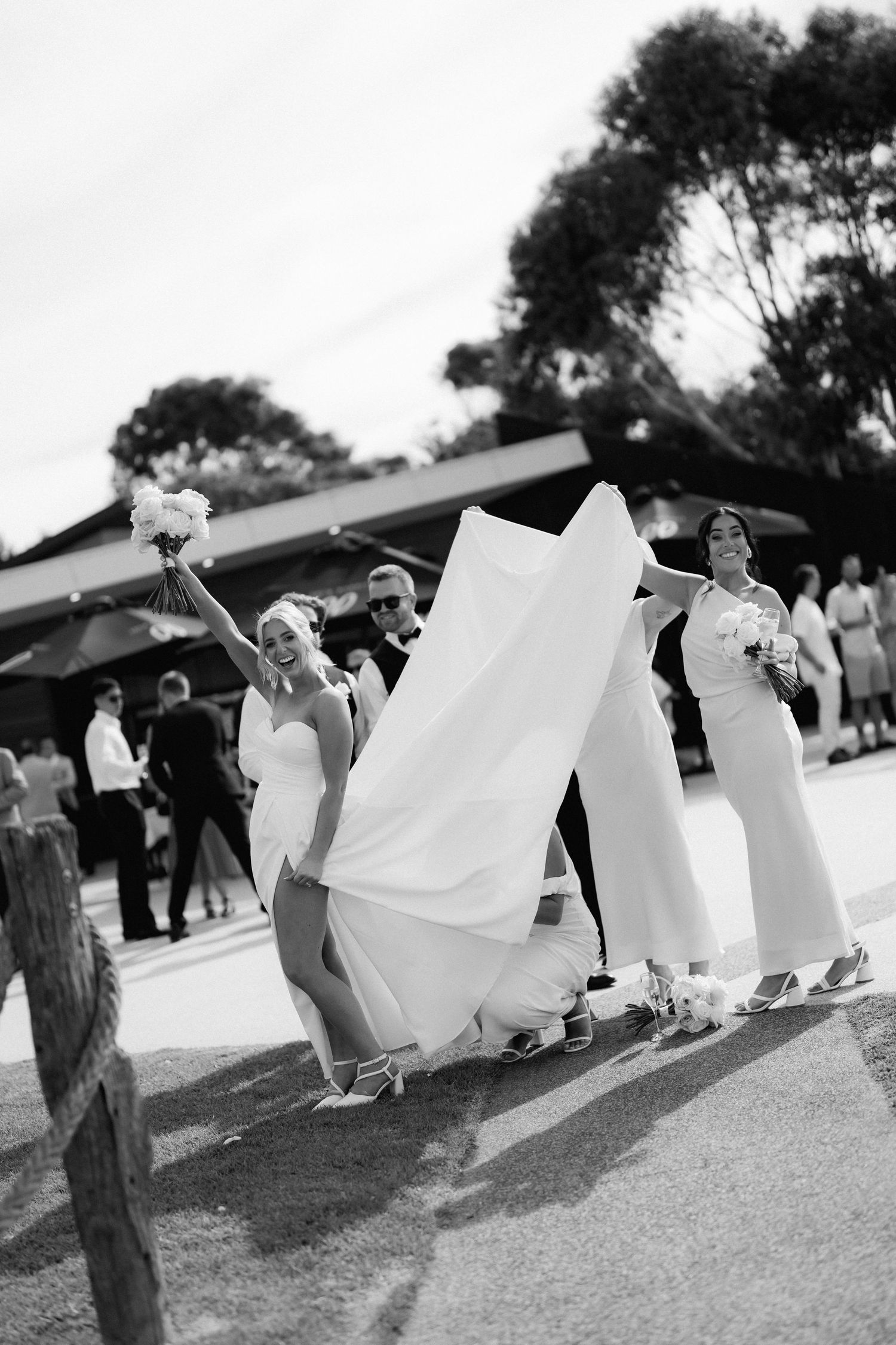 A black and white photo of wedding guests dancing and celebrating outdoors.