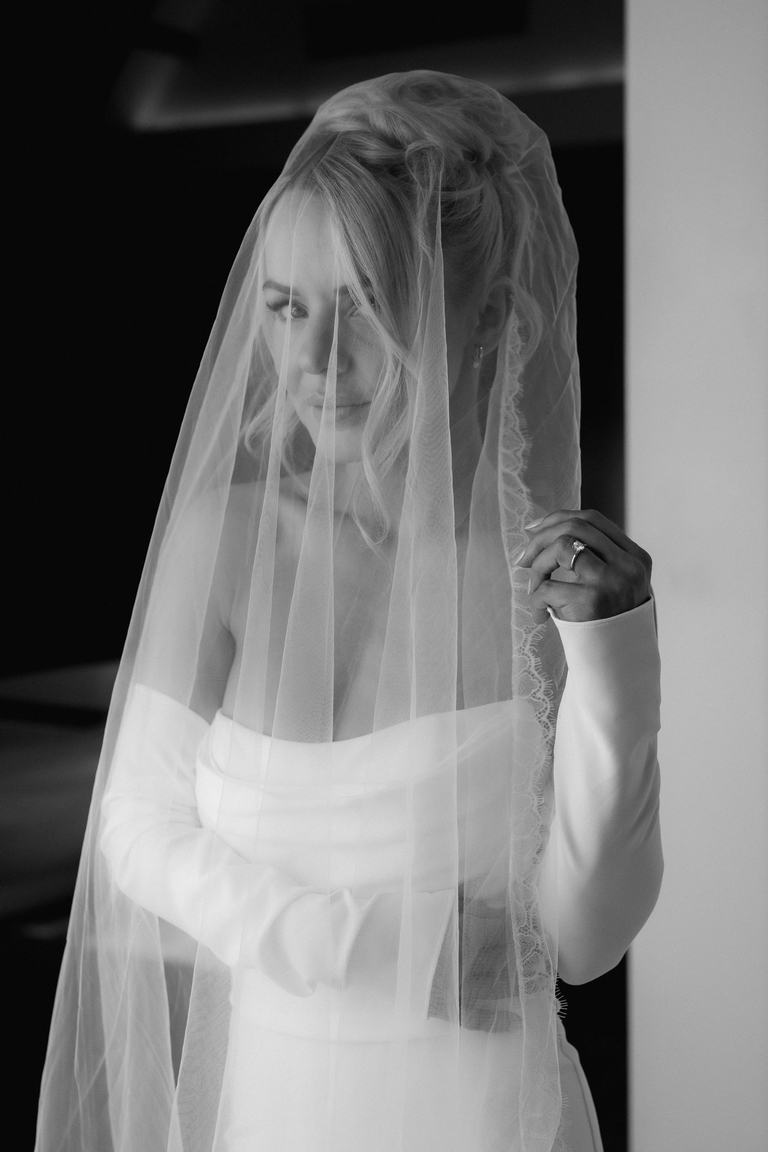 Black and white portrait of bride wearing delicate sheer veil with soft natural lighting.