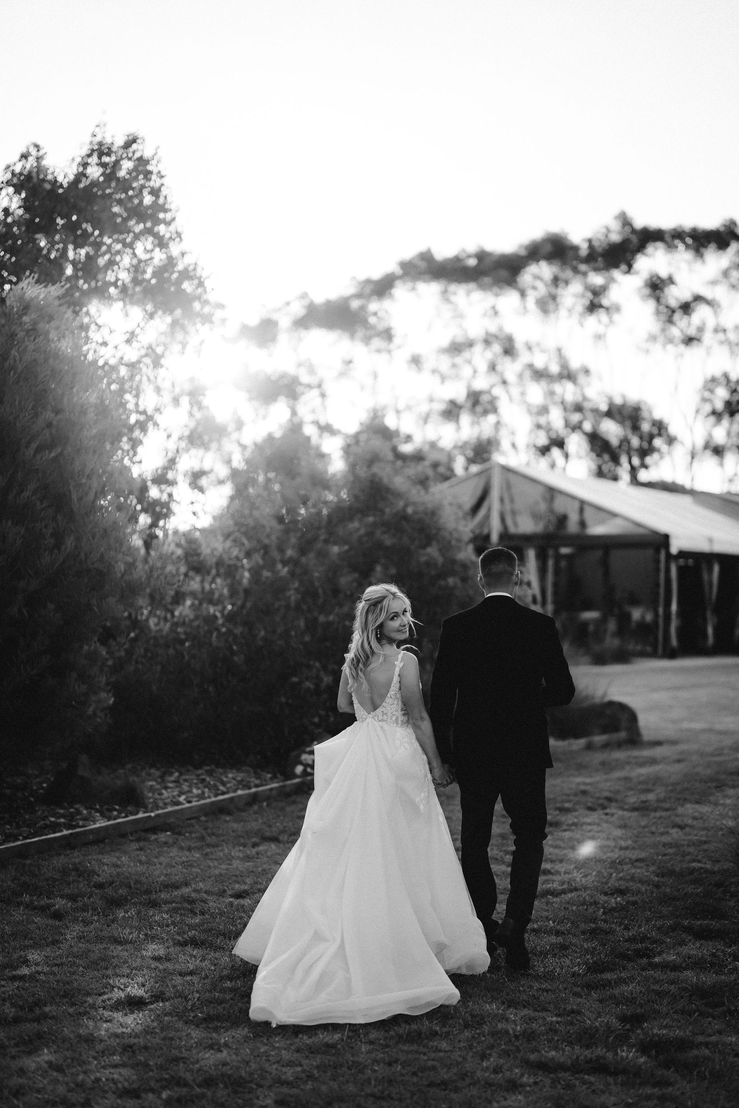 Black and white silhouette of newlyweds walking together during sunset.