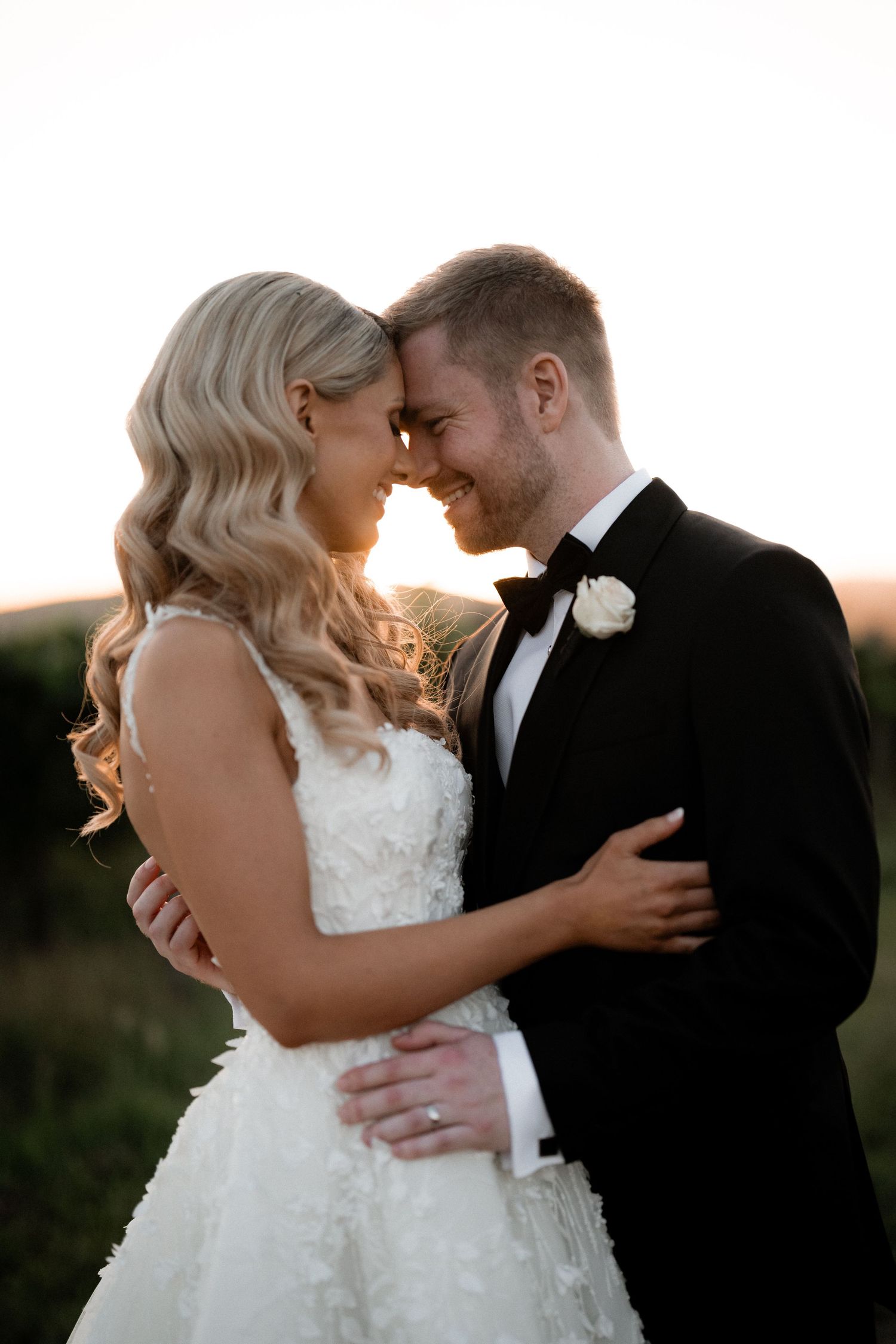 A tender wedding portrait captures a romantic moment between a couple during golden hour.