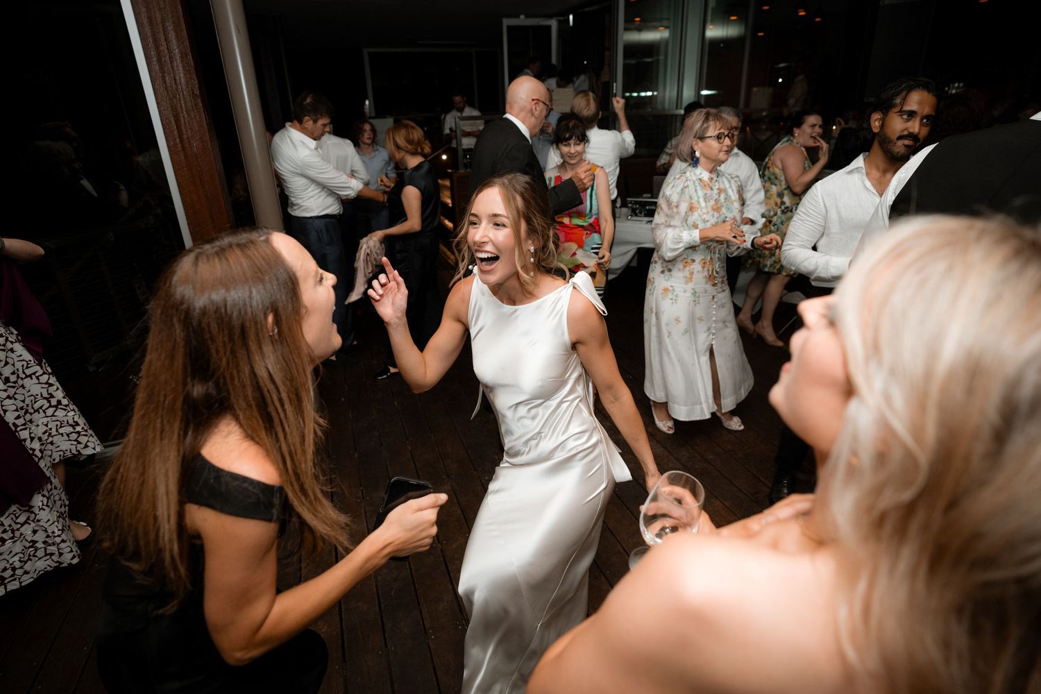 Wedding party dancing and having fun at a reception with guests moving to the music on the dance floor.