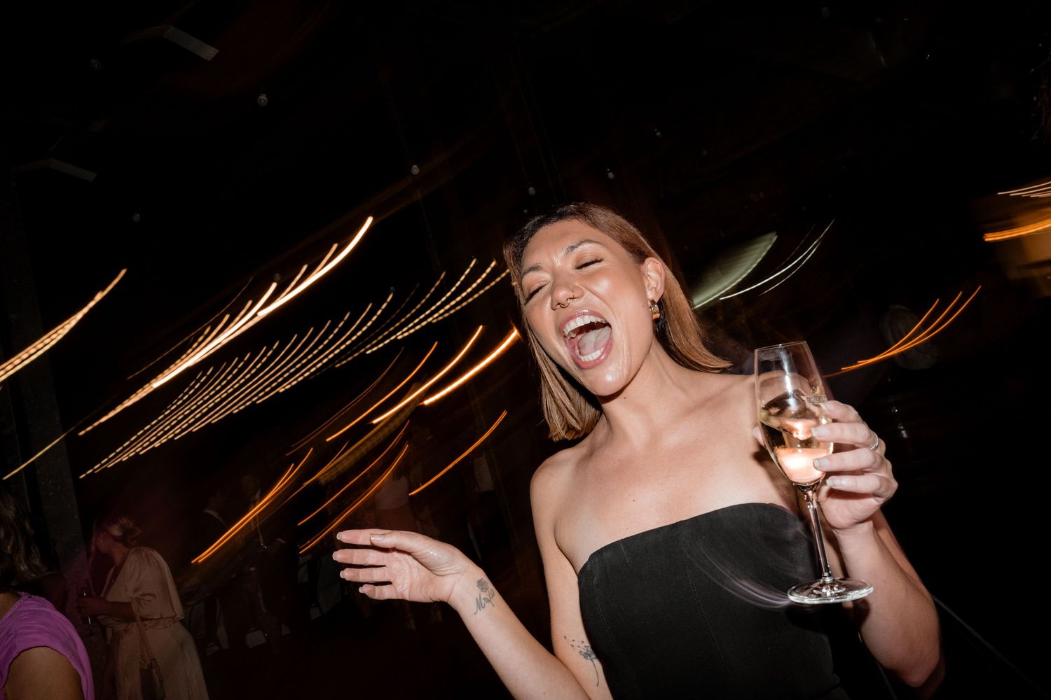 Wedding guests dancing and celebrating on a dark dance floor with dramatic lighting effects.