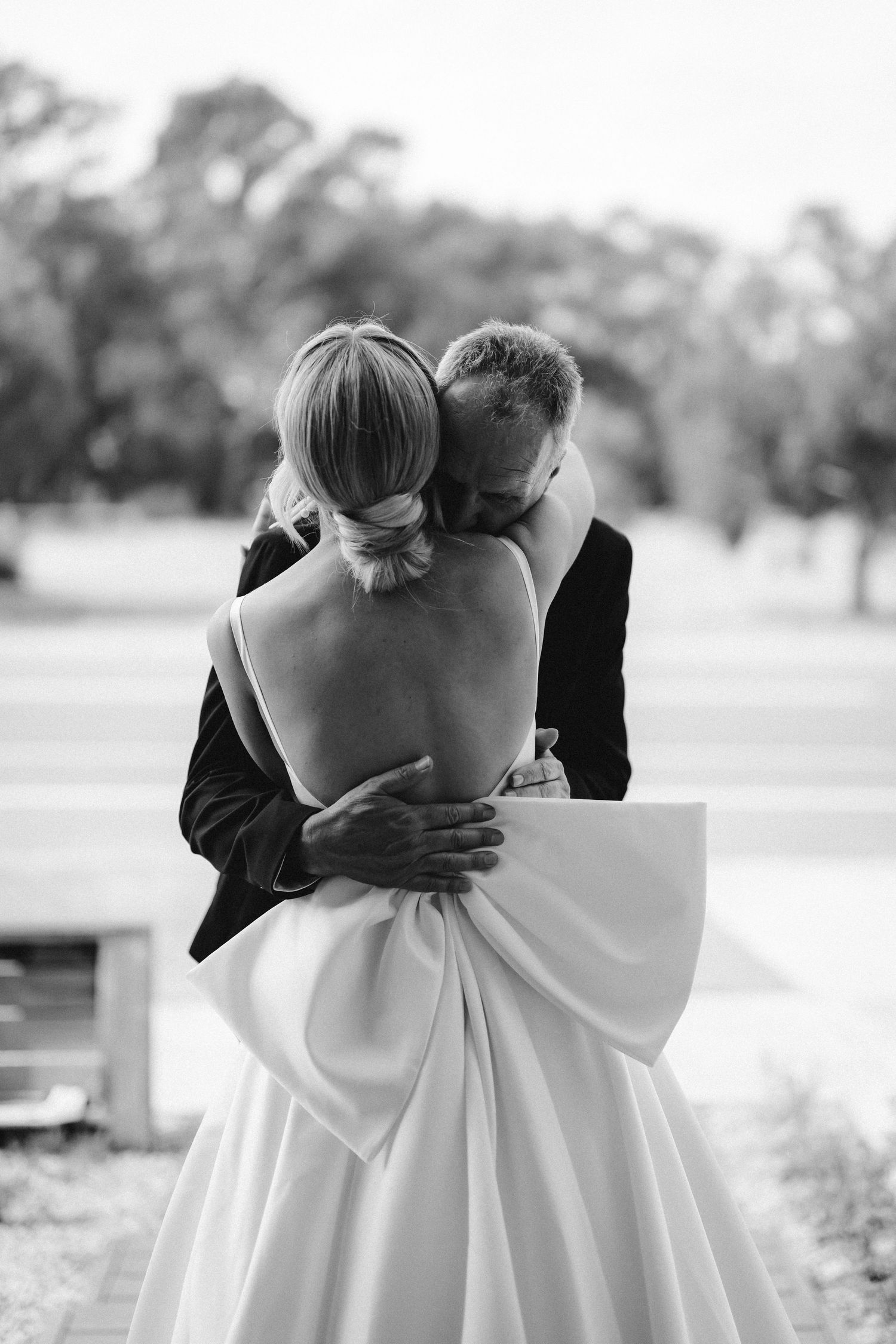 Romantic black and white wedding photo showing a couple embracing, with the bride wearing an elegant backless gown.