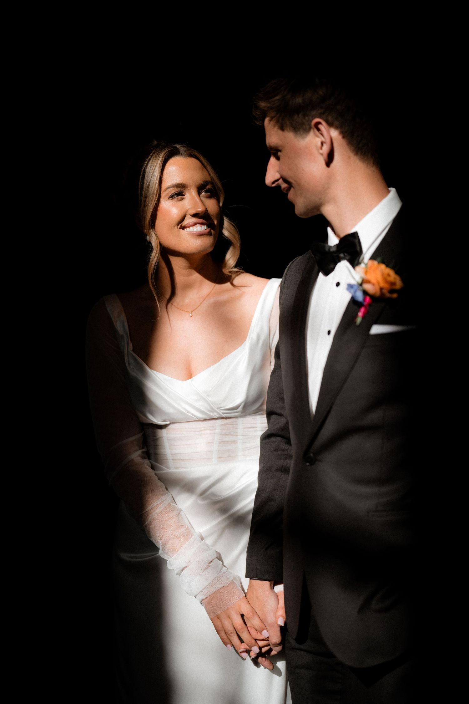 Elegant wedding couple sharing an intimate moment in dramatic lighting.