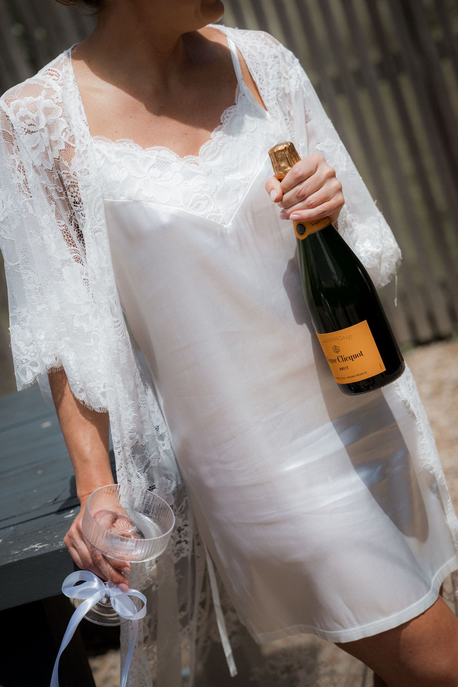 Elegant white lace wedding dress with champagne bottle details.