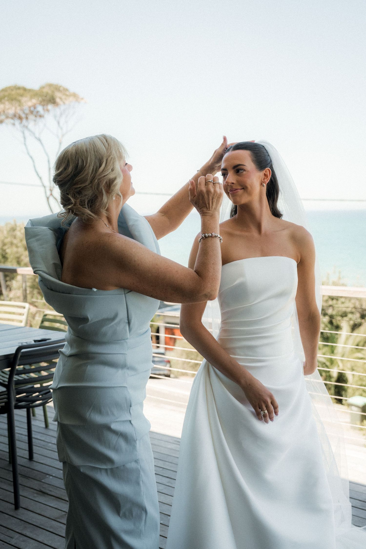 Candid sequence of two people in formal attire sharing a joyful moment on an oceanview deck.