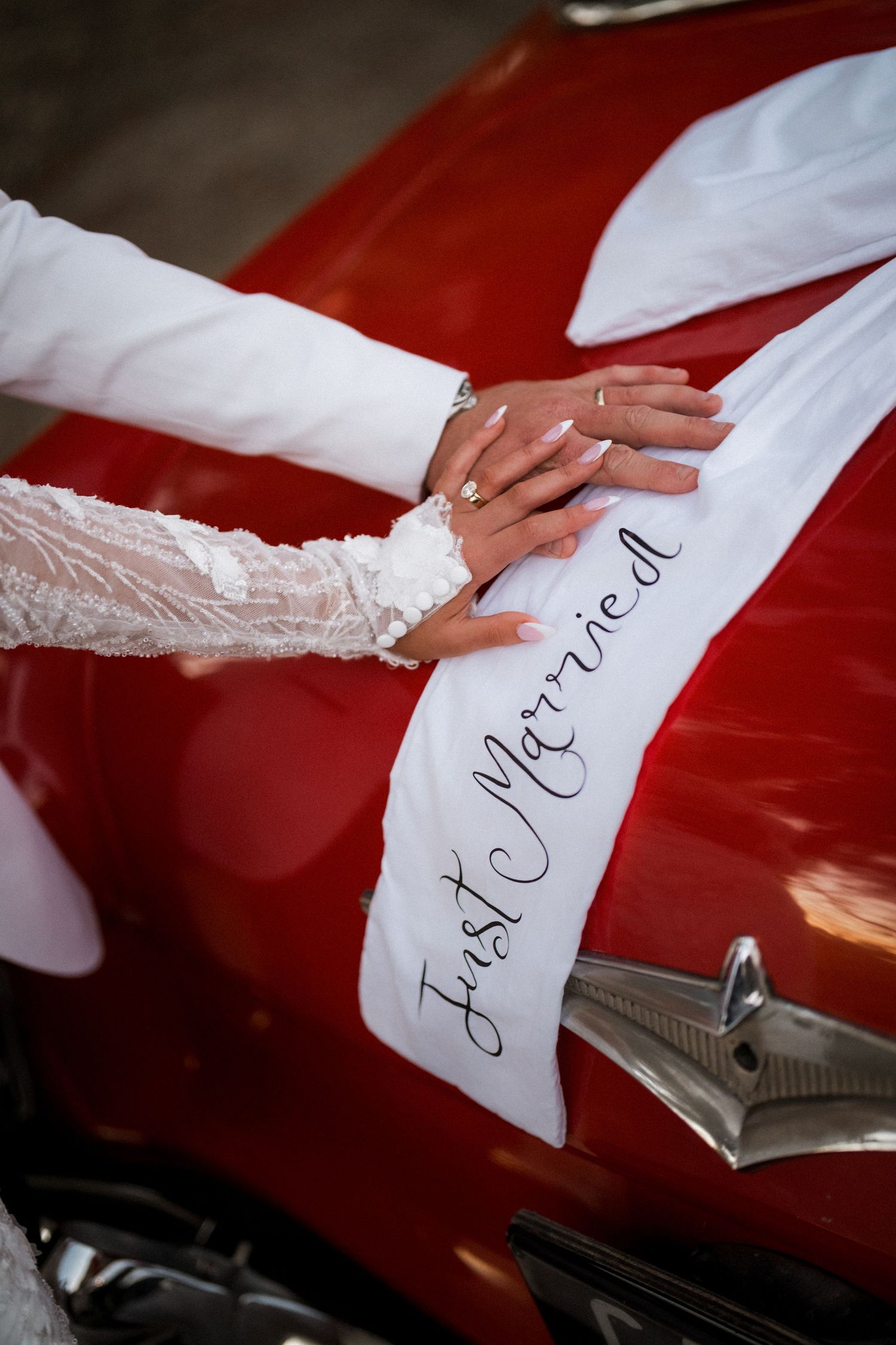 A hand in white lace writes a message on a red surface with a pen.