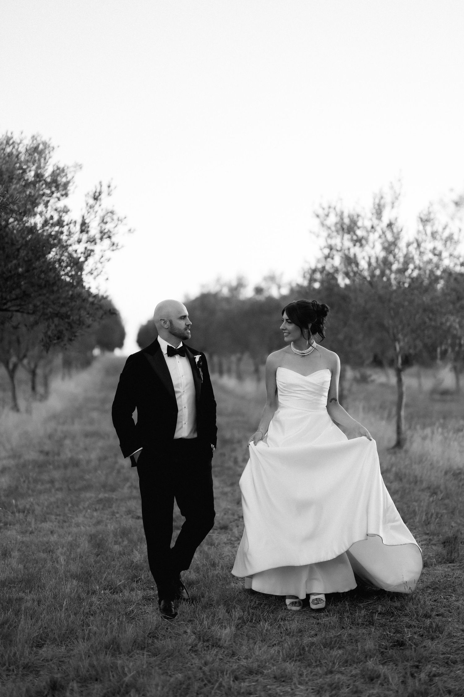 Black and white photo sequence of newlyweds sitting together in rustic field.