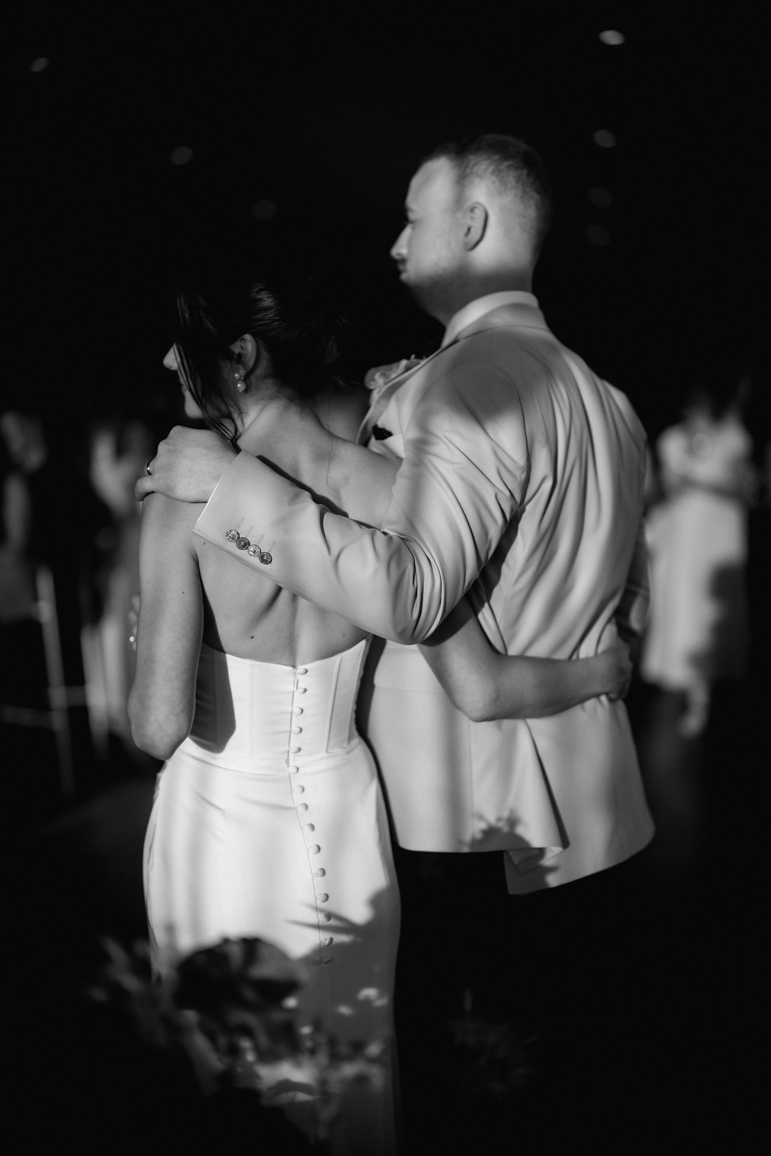 A couple shares their first dance at a wedding reception, captured in elegant black and white photography.