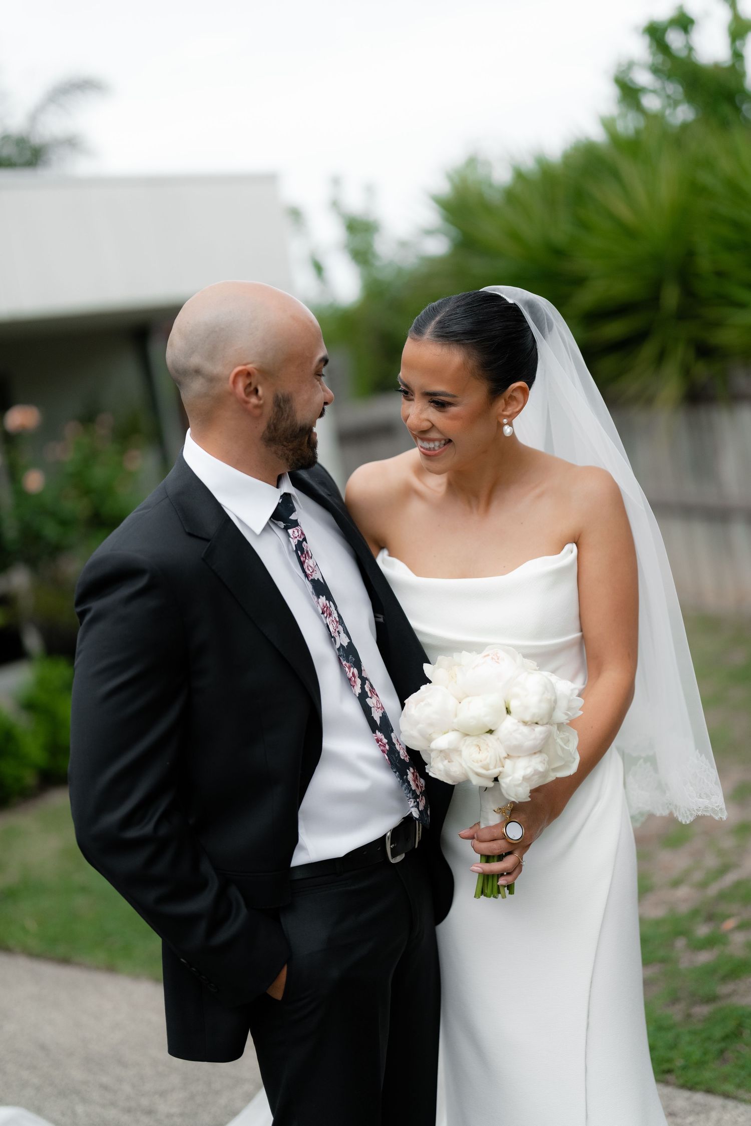 A happy couple shares a joyful moment on their wedding day with the bride holding a white bouquet.