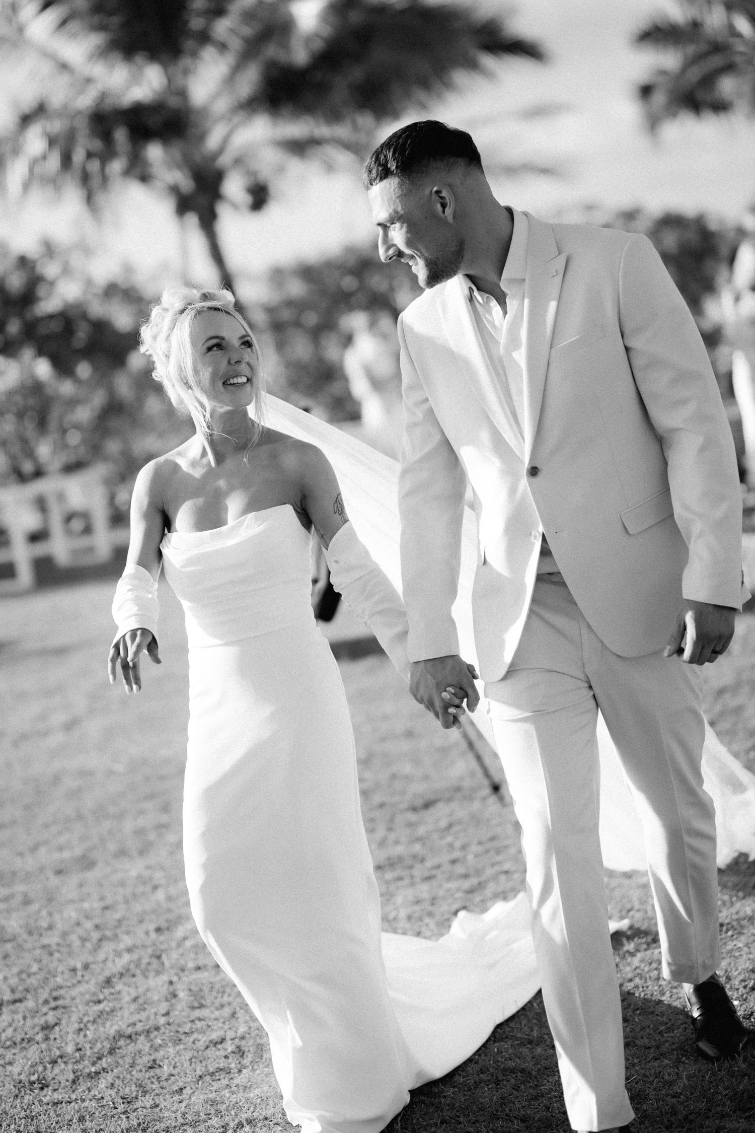 Black and white portrait of a joyful wedding couple walking outdoors.