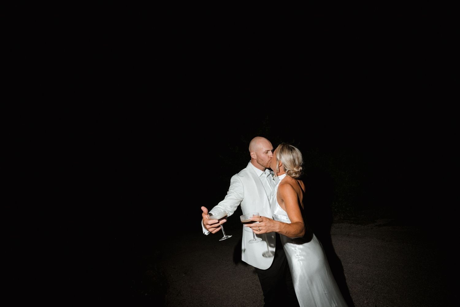 A couple shares an intimate dance moment silhouetted against a dark background.