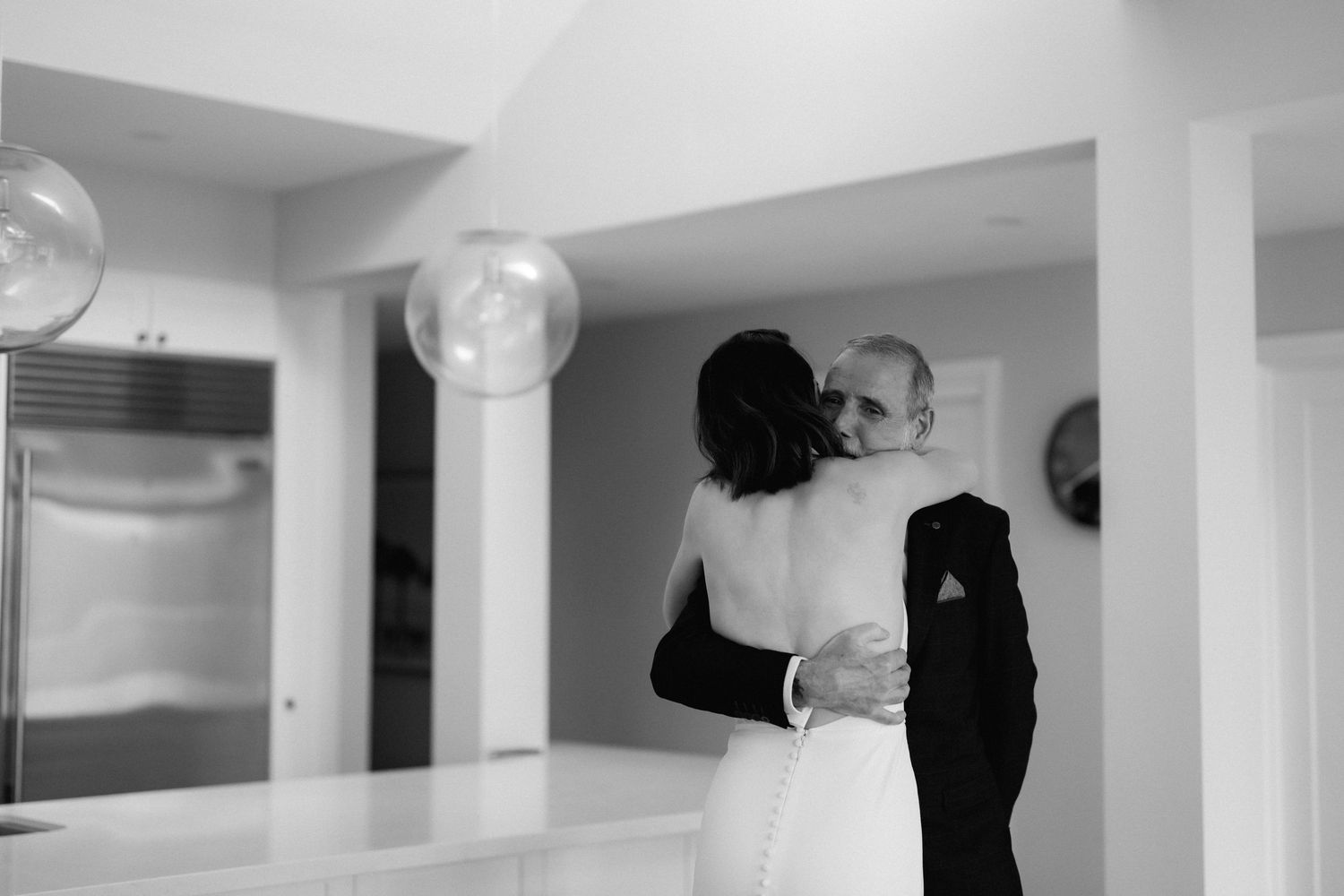 A couple shares an intimate dance moment in a black and white photograph at an indoor venue.