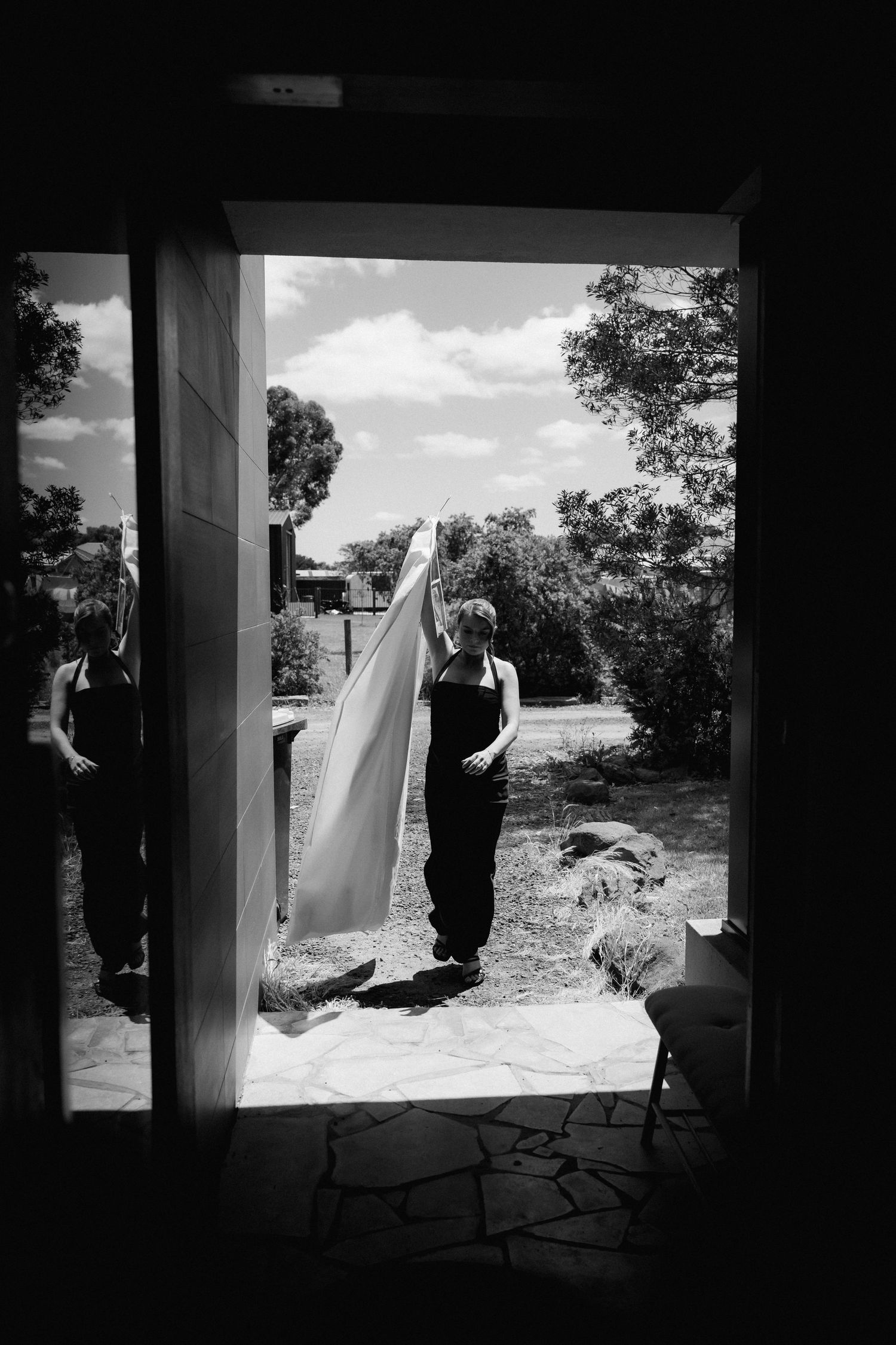 Black and white wedding photos show silhouettes of figures against bright doorway in artistic composition.