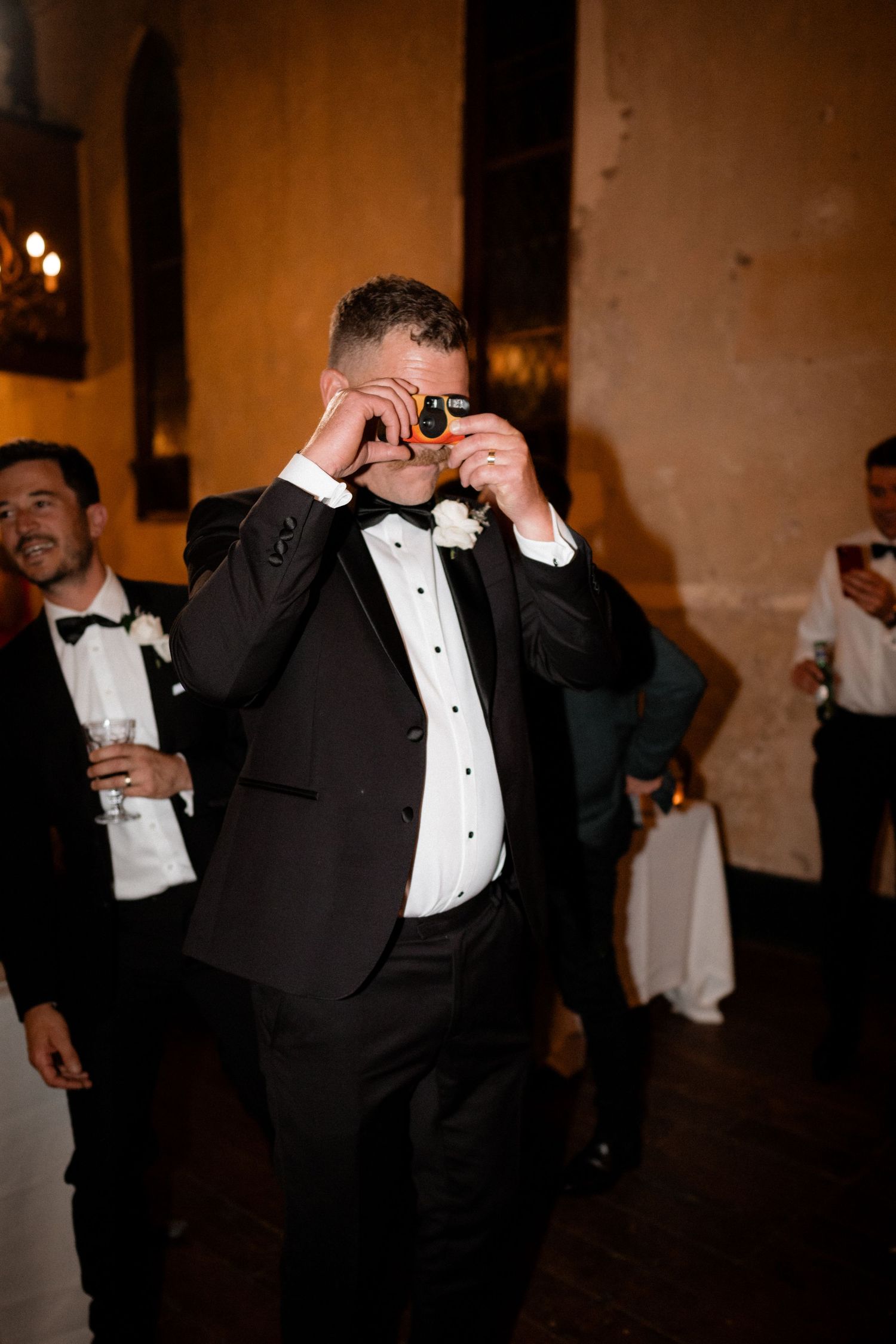 Wedding reception guests in formal attire celebrate on the dance floor.