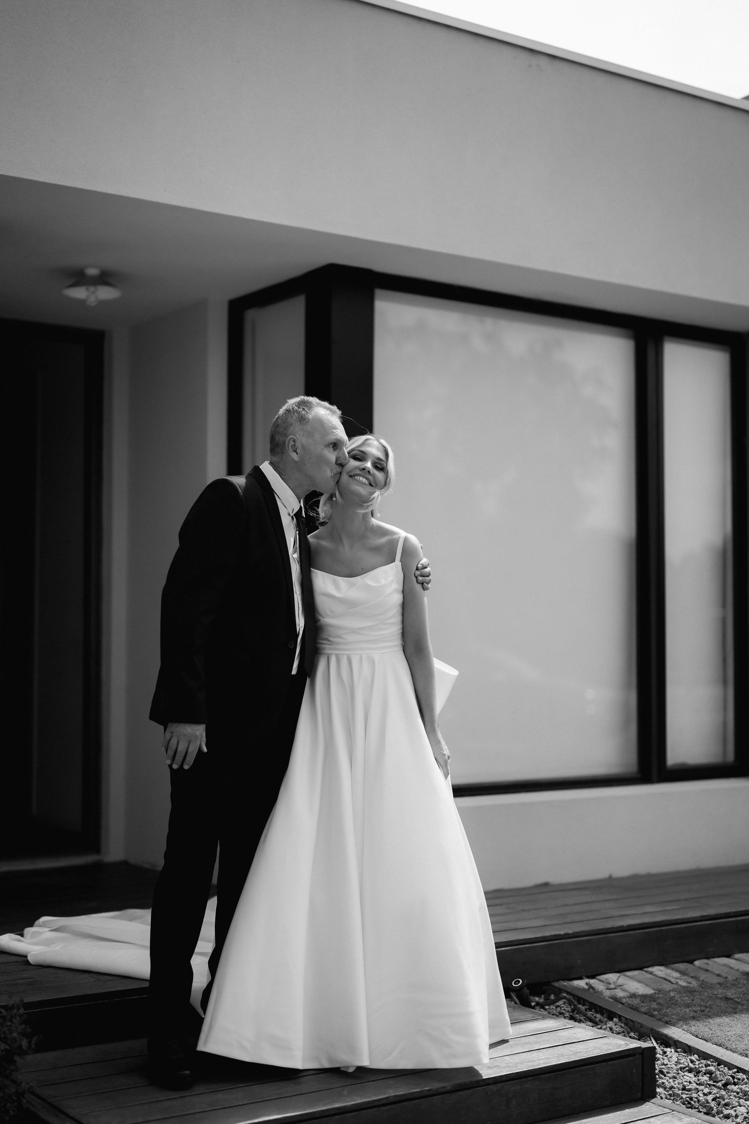 A series of black and white photos showing a bride in a flowing white dress walking through a modern hallway.