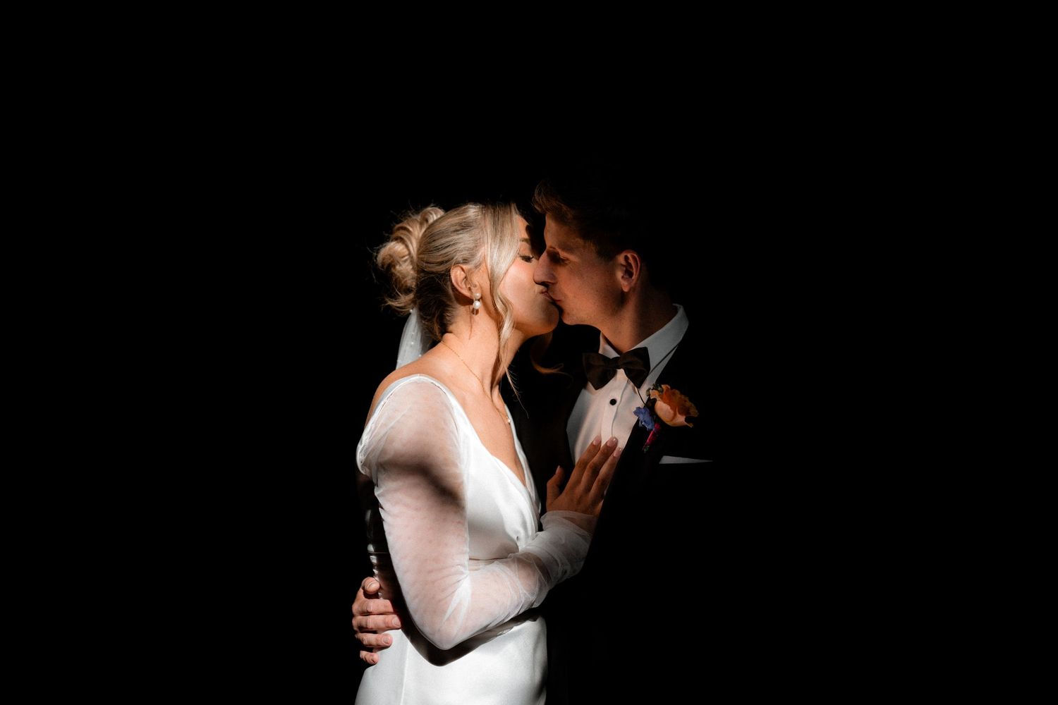 Silhouetted romantic dance poses against dark background at wedding reception.
