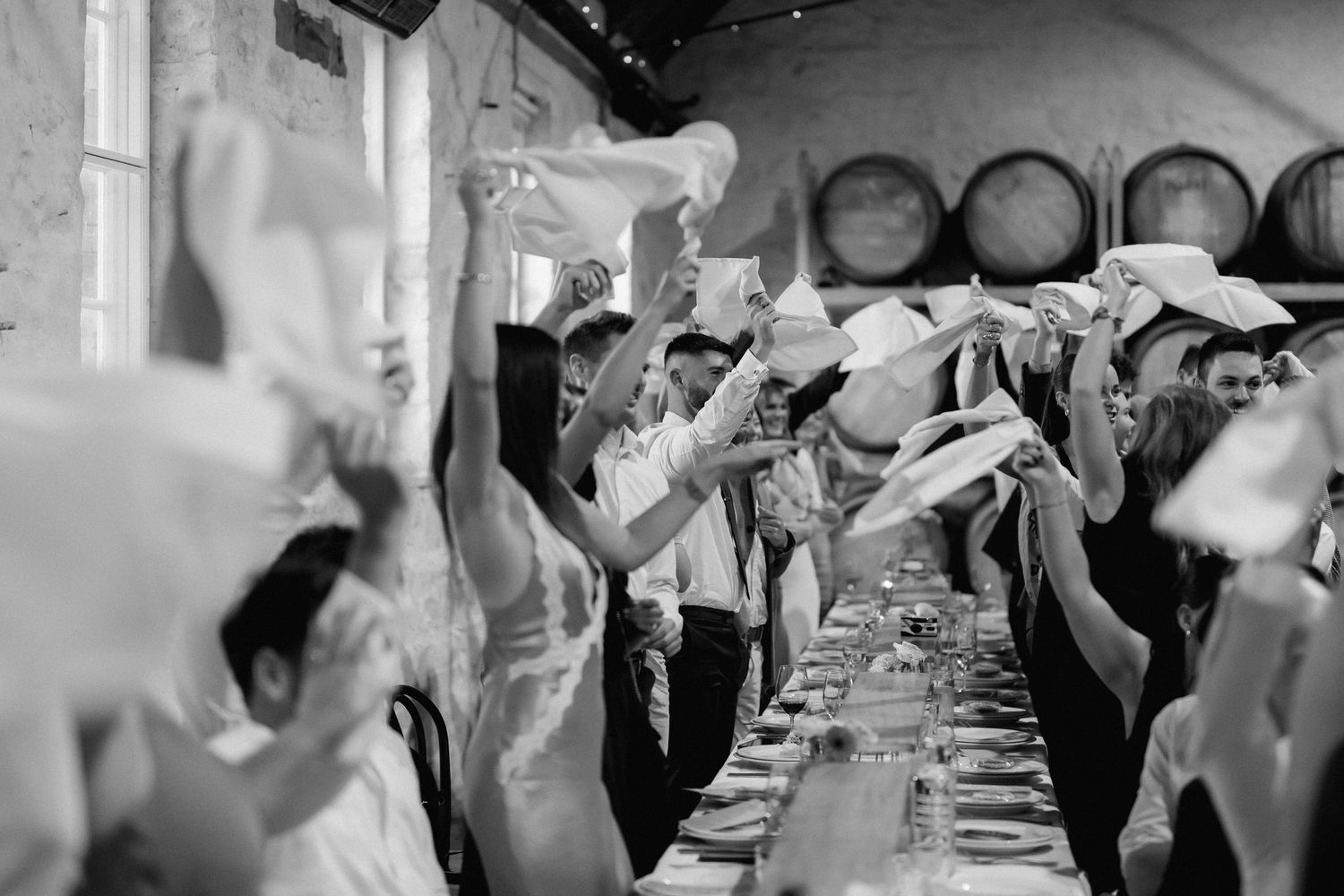 Wedding reception guests raising glasses in celebration at dining tables.
