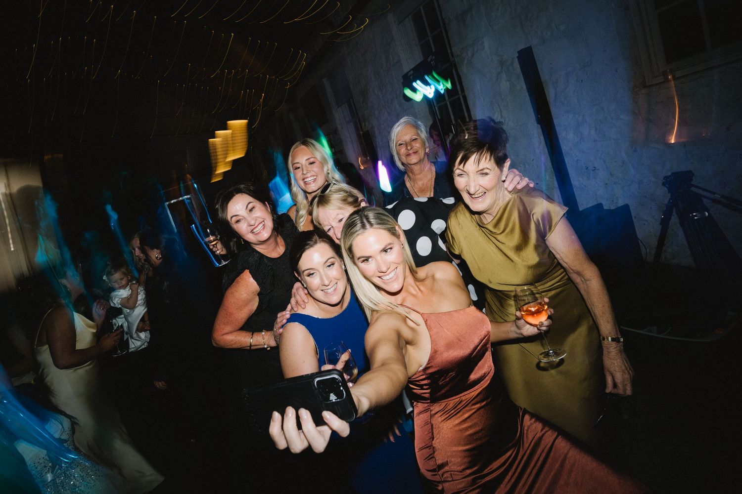 A group of people smiling and posing together at a nightclub with blue lighting in the background.