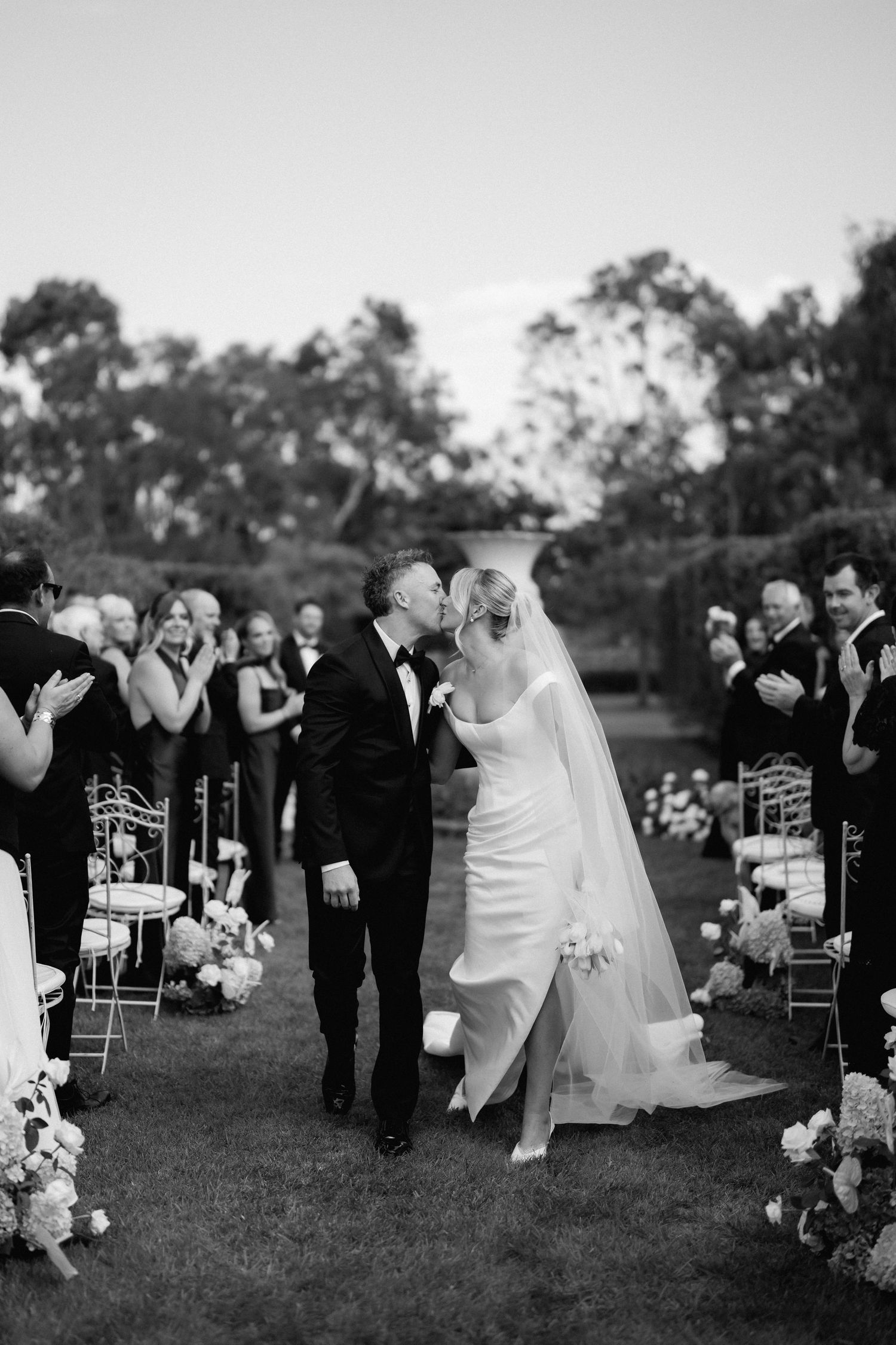 Wedding party performs choreographed dance move during outdoor celebration.