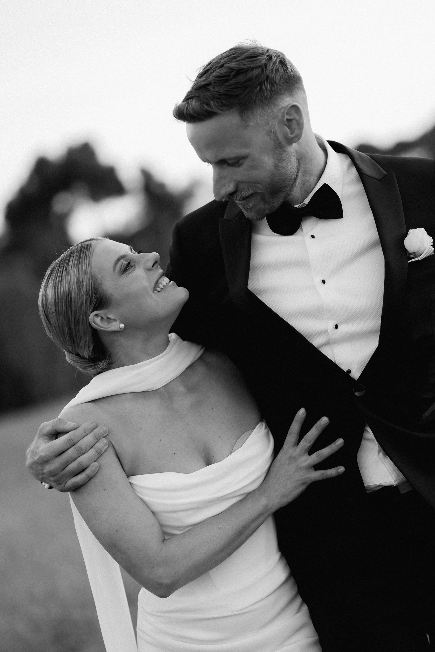 A romantic black and white photo series showing a couple in formal wedding attire embracing in tender moments.