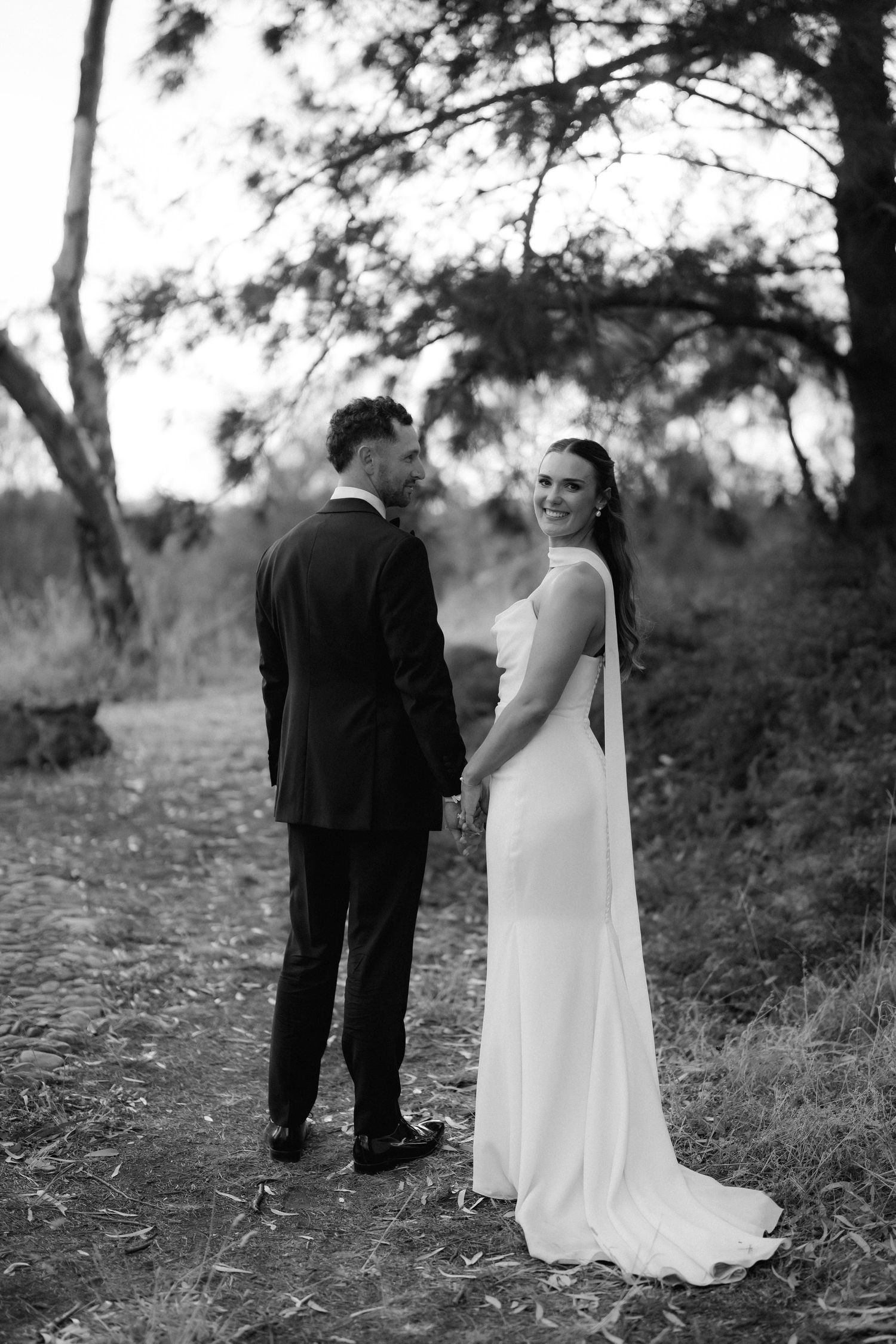 A series of romantic black and white wedding photos showing a couple in formal attire walking outdoors.